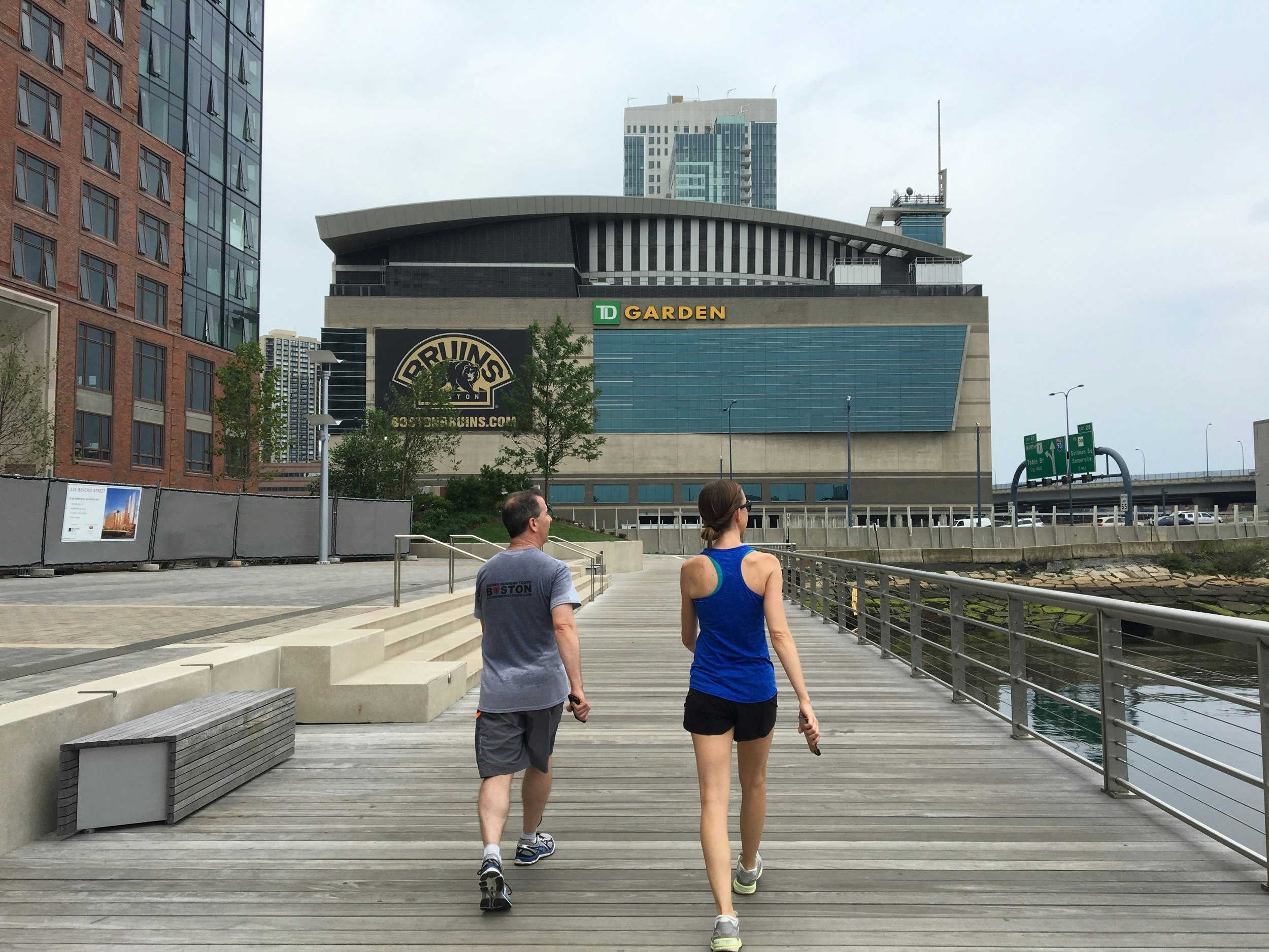 A man and a woman sweat as they take a break from running along the boardwalk at Boston Harbor