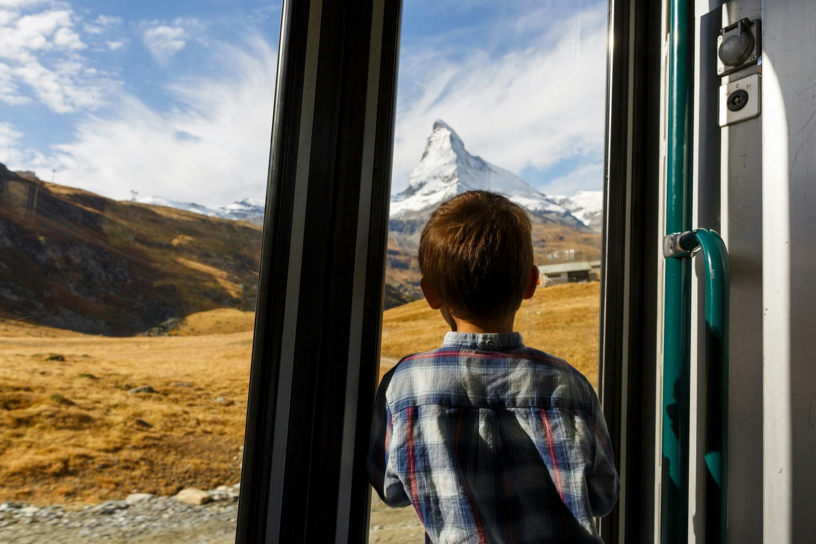 Boy looks out the window of a train towards the Matterhorn
