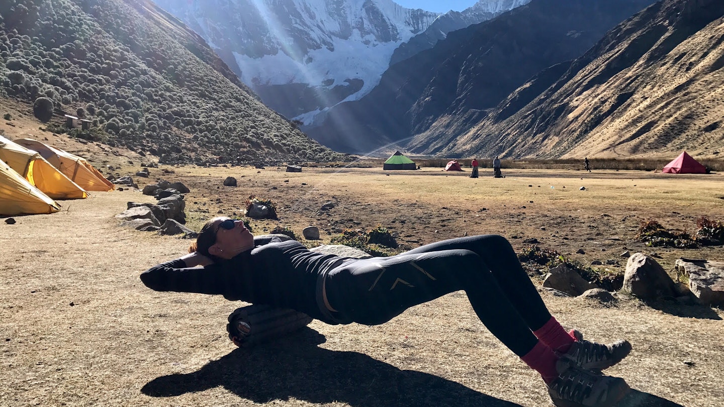 A woman lying on a Brazyn Morph collapsible foam roller at a campsite in the Andes mountains