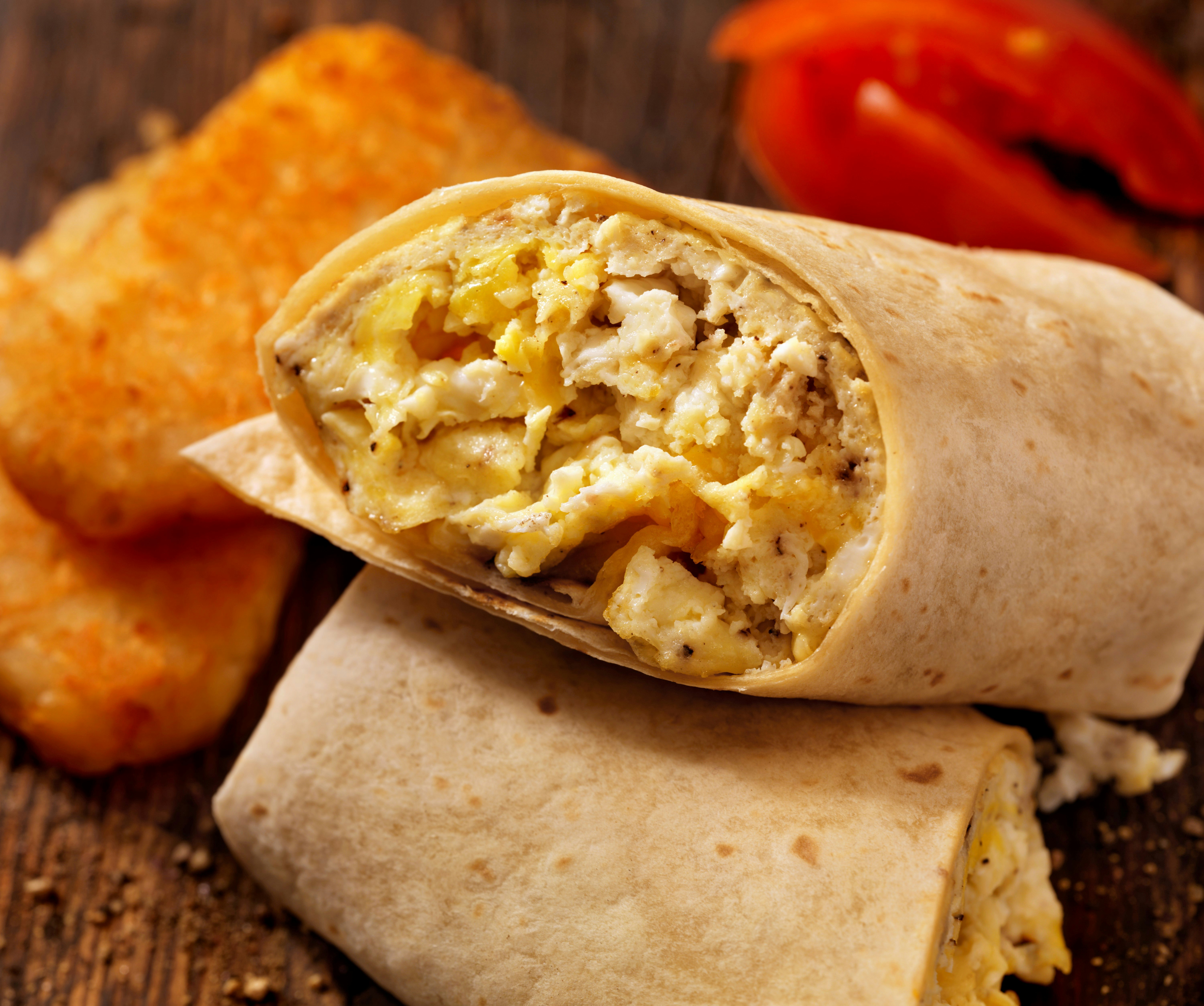 En närbild av en frukostburrito: ägg och ost insvept i en tortilla. 