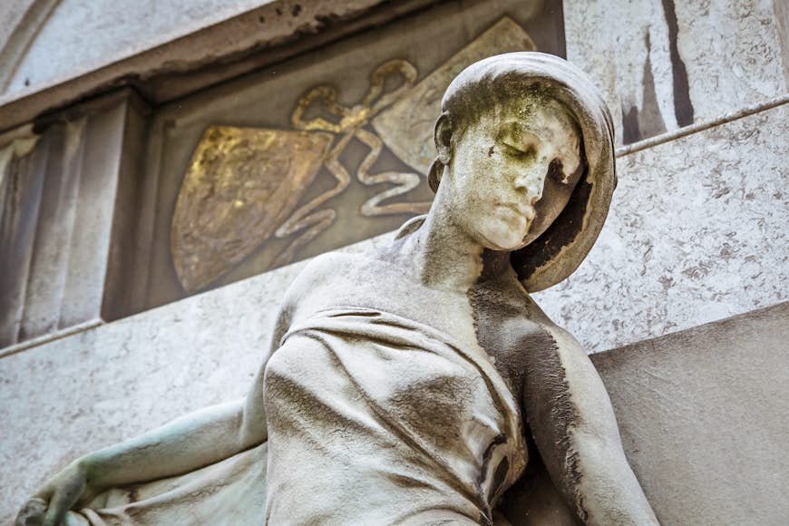 A closeup of statue of a women's face and upper body in front of a mausoleum at the Kerepesi Cemetery; Budapest autumn  