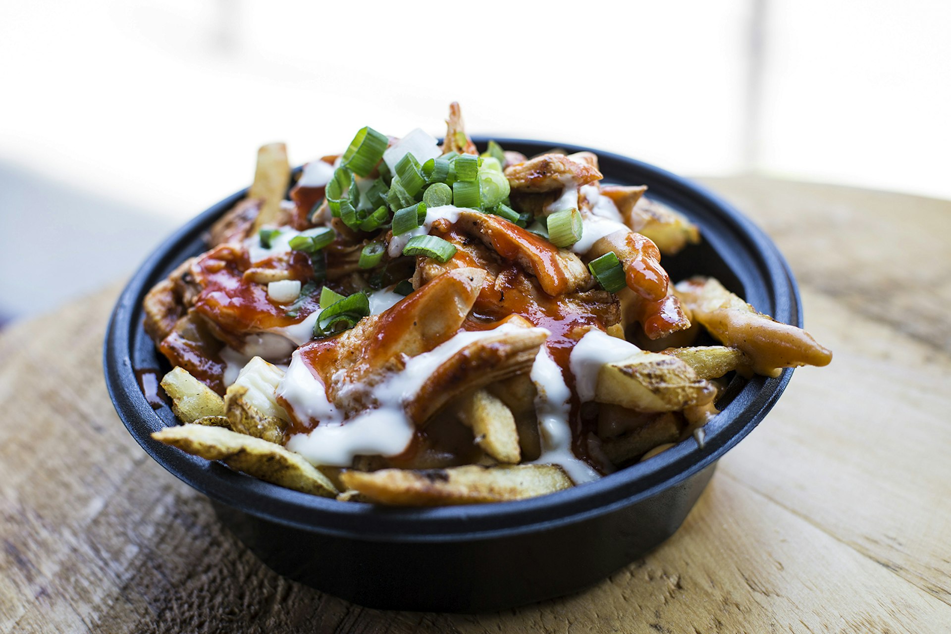 A close-up of buffalo chicken poutine topped with green onions at Allen Street Poutine. Buffalo, NY.