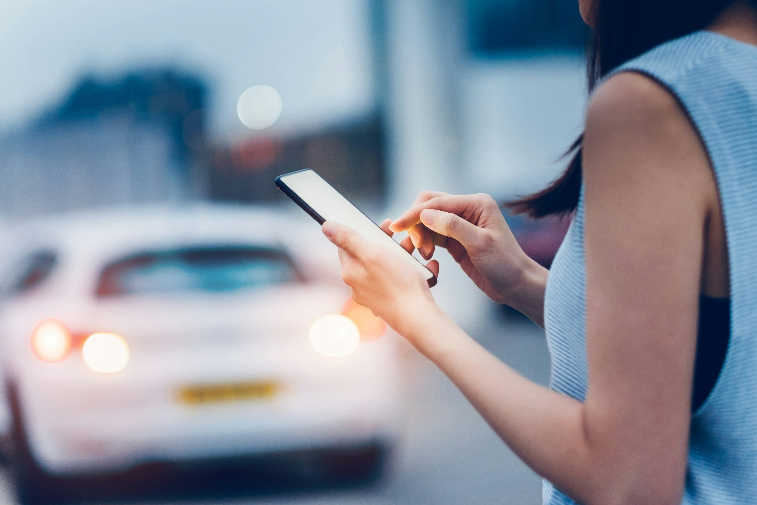 A woman with a phone in her hand and a cab in the background