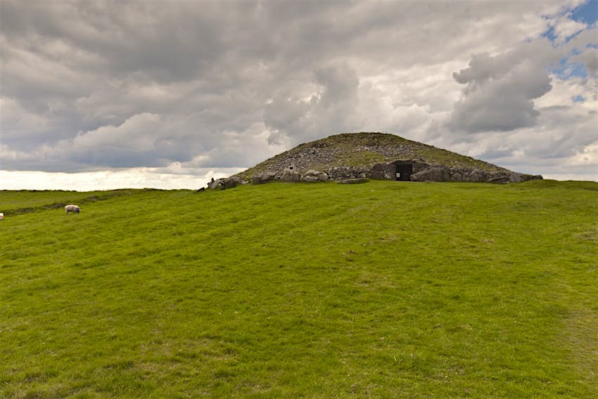 A large stone tomb sits atop a green hilltop in Loughcrew Ireland 