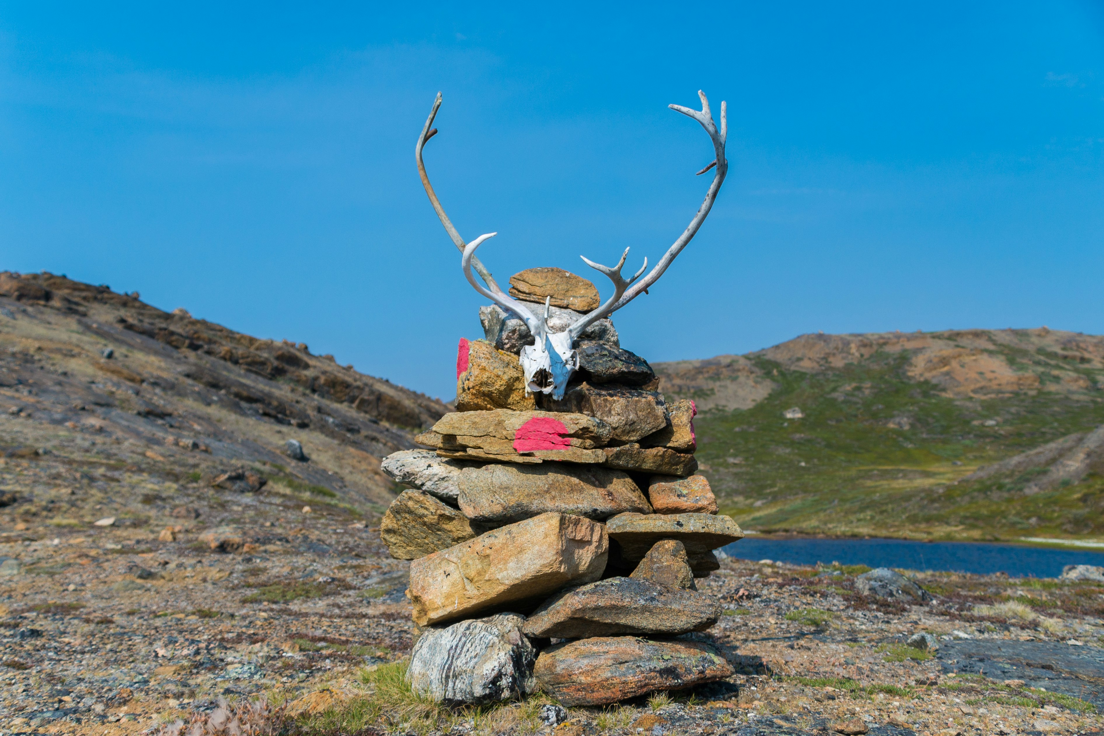A cairn of stacked stones crowned by reindeer antlers marking the route on the Arctic Circle Trail.