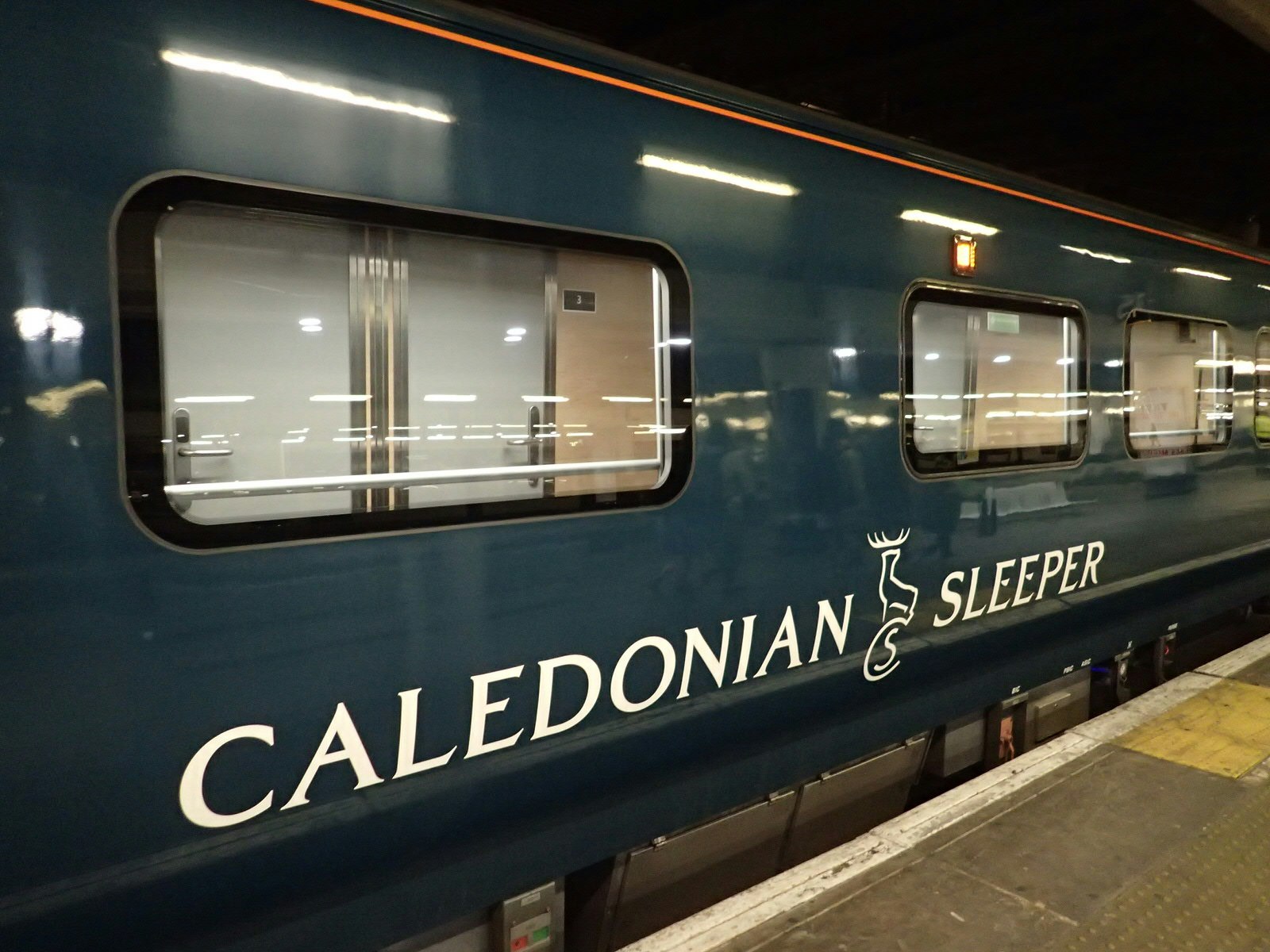 Caledonian Sleeper train exterior. The logo is written in white against the dark green body of the train carriage. 