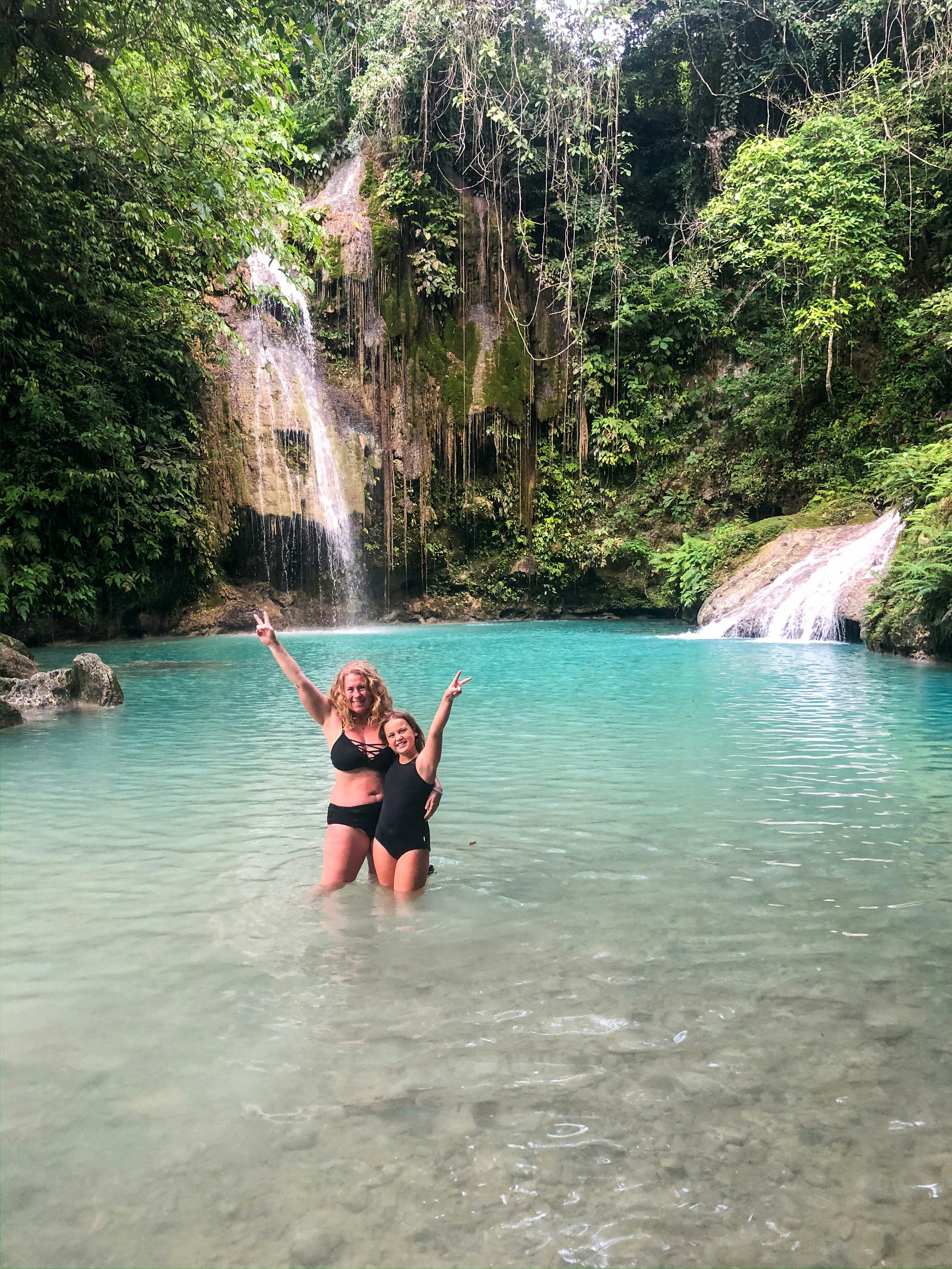 Evie and Emmie stand in the bright turquoise natural pool at picturesque Cambias Falls, Cebu.