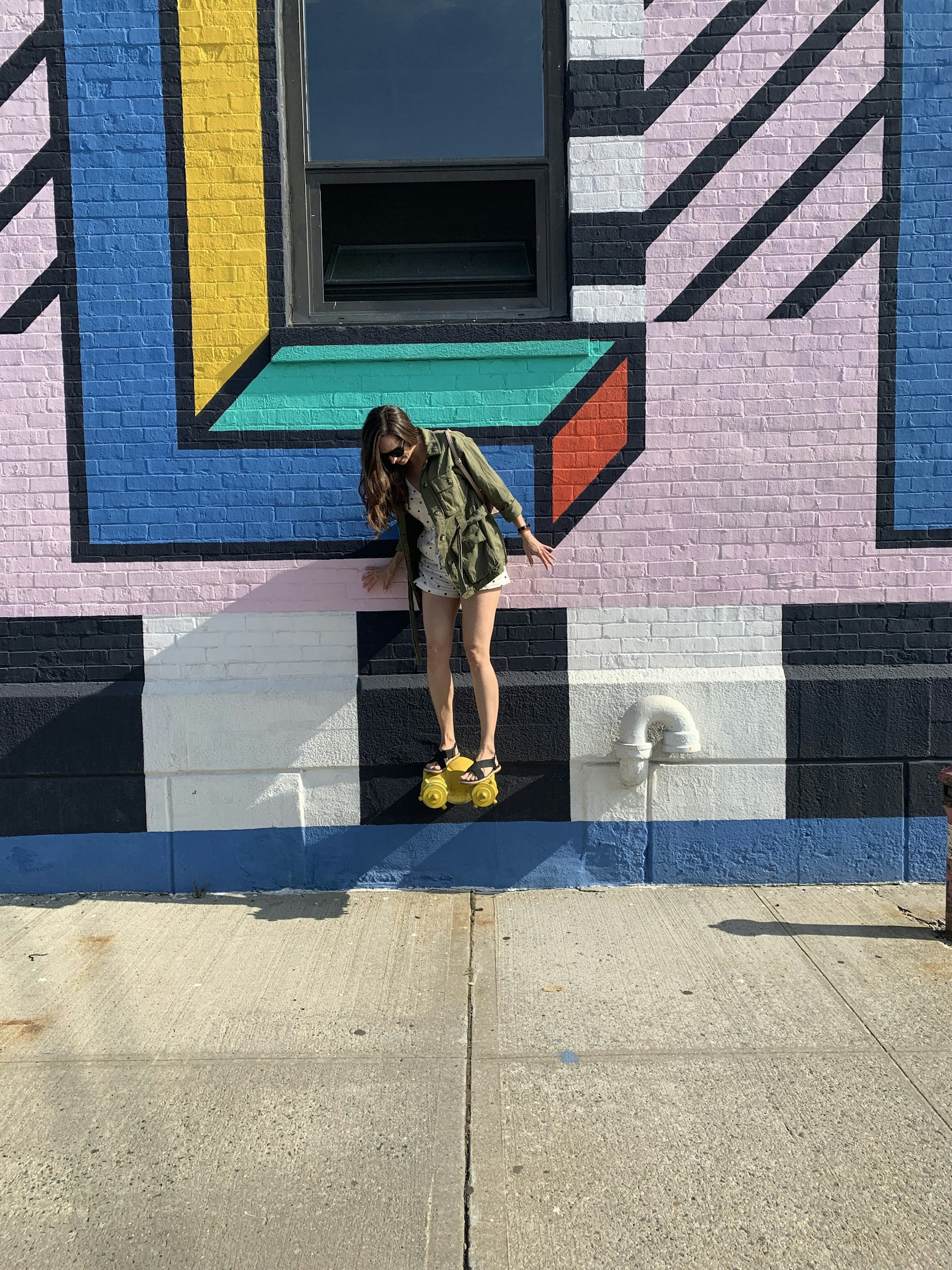 The writer balances on a yellow fire hydrant in front of a colourful wall mural.