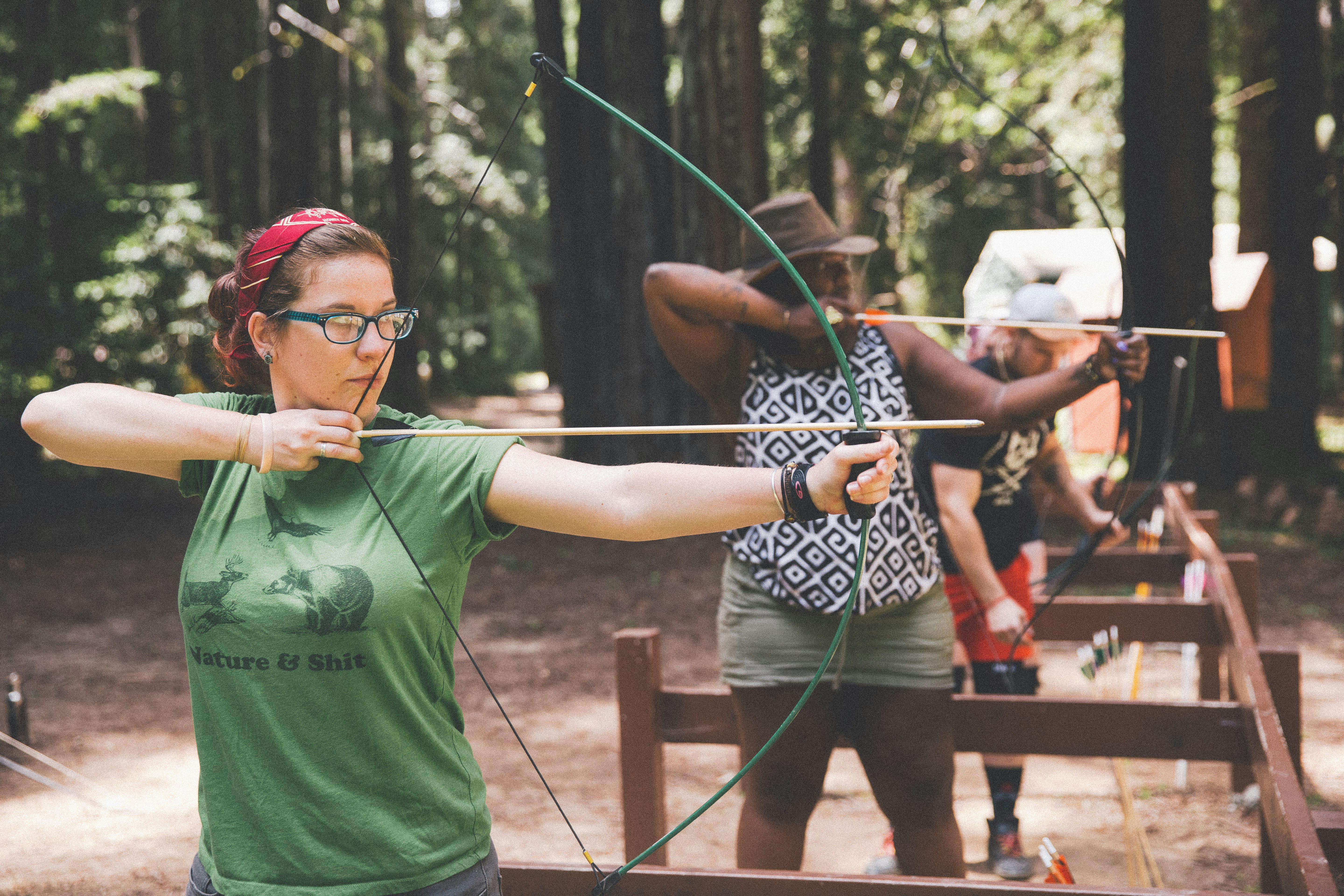 Three people with bows and arrows, shooting