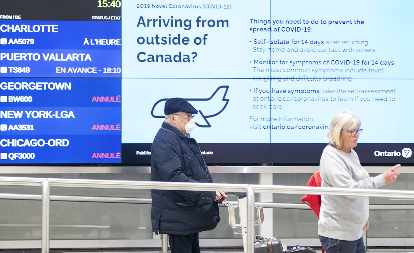 Travelers arrive at the Pearson International Airport in Toronto, Canada, on March 26, 2020. Canada imposed a 14-day mandatory self-isolation rule for any traveler returning to Canada. 