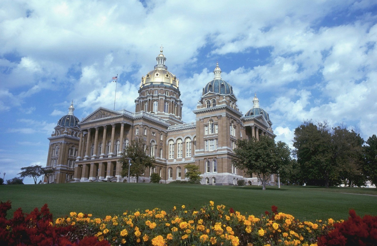 Flowers dominate the foreground in a landscaped park as the Iowa state capitol stands on a hill behind; Things to do in Des Moines during the Iowa Caucuses
