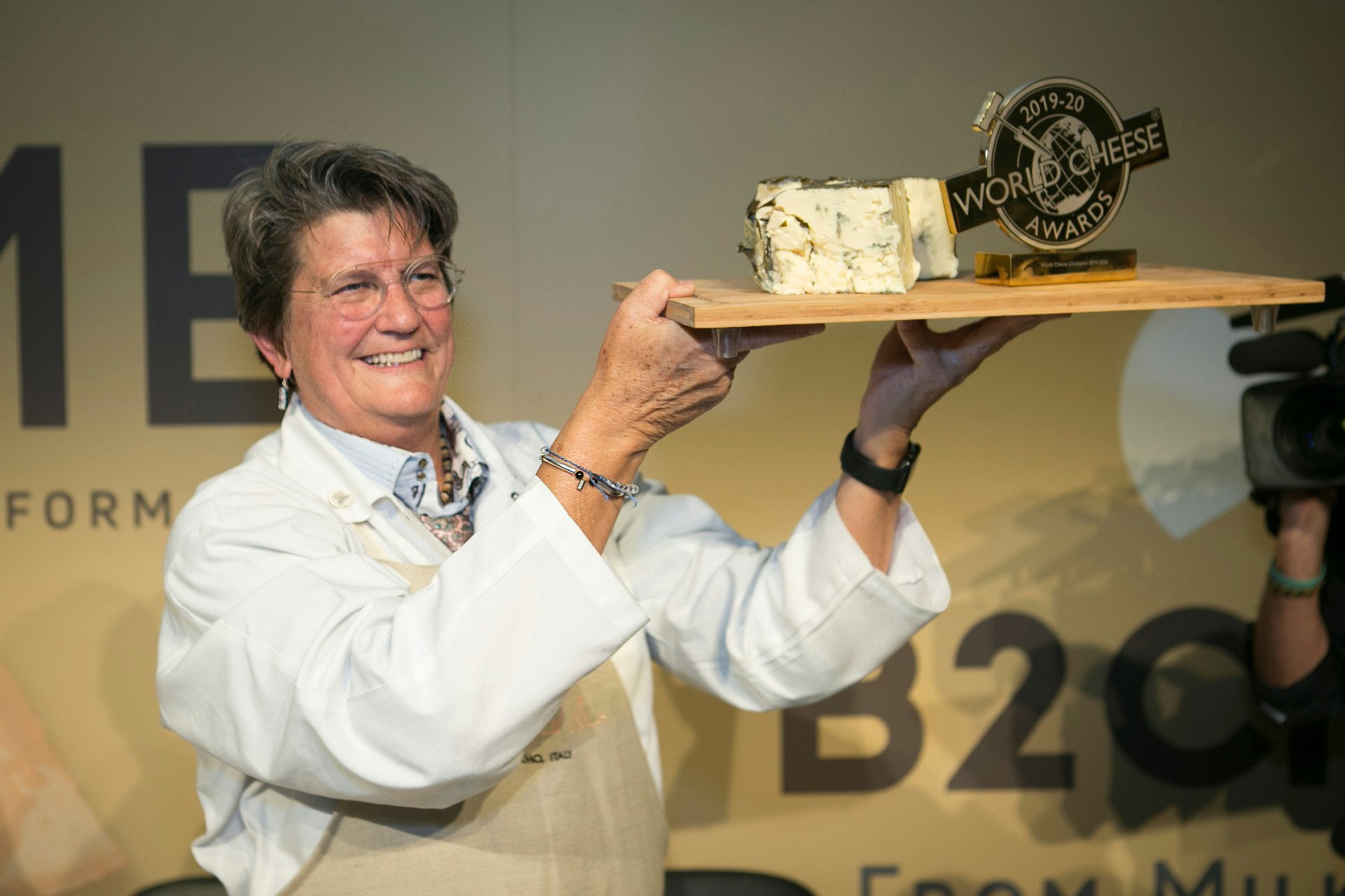 A female judge holds up a plate of the organic blue cheese and a gold award
