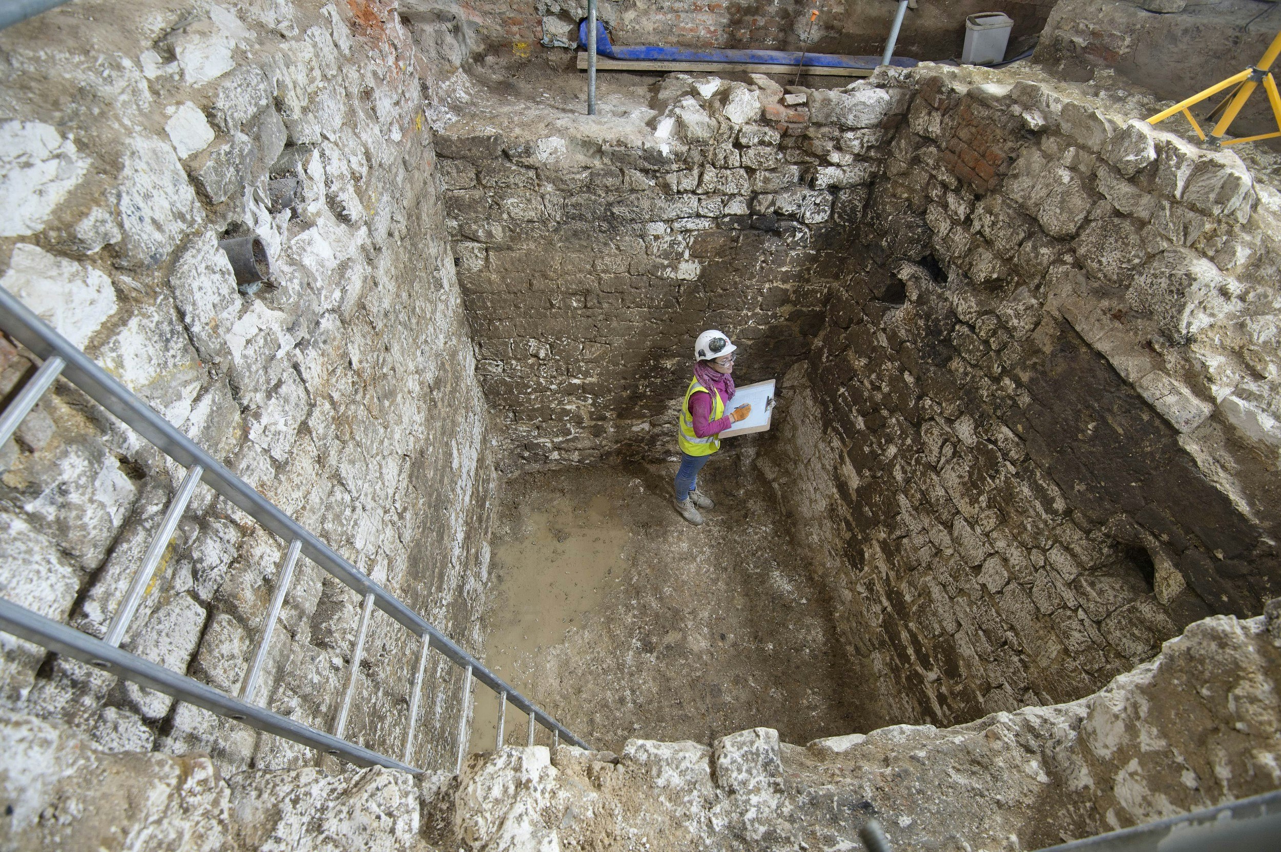 A MOLA archaeologist recording a 15th century cesspit uncovered in the basement of the Courtauld
