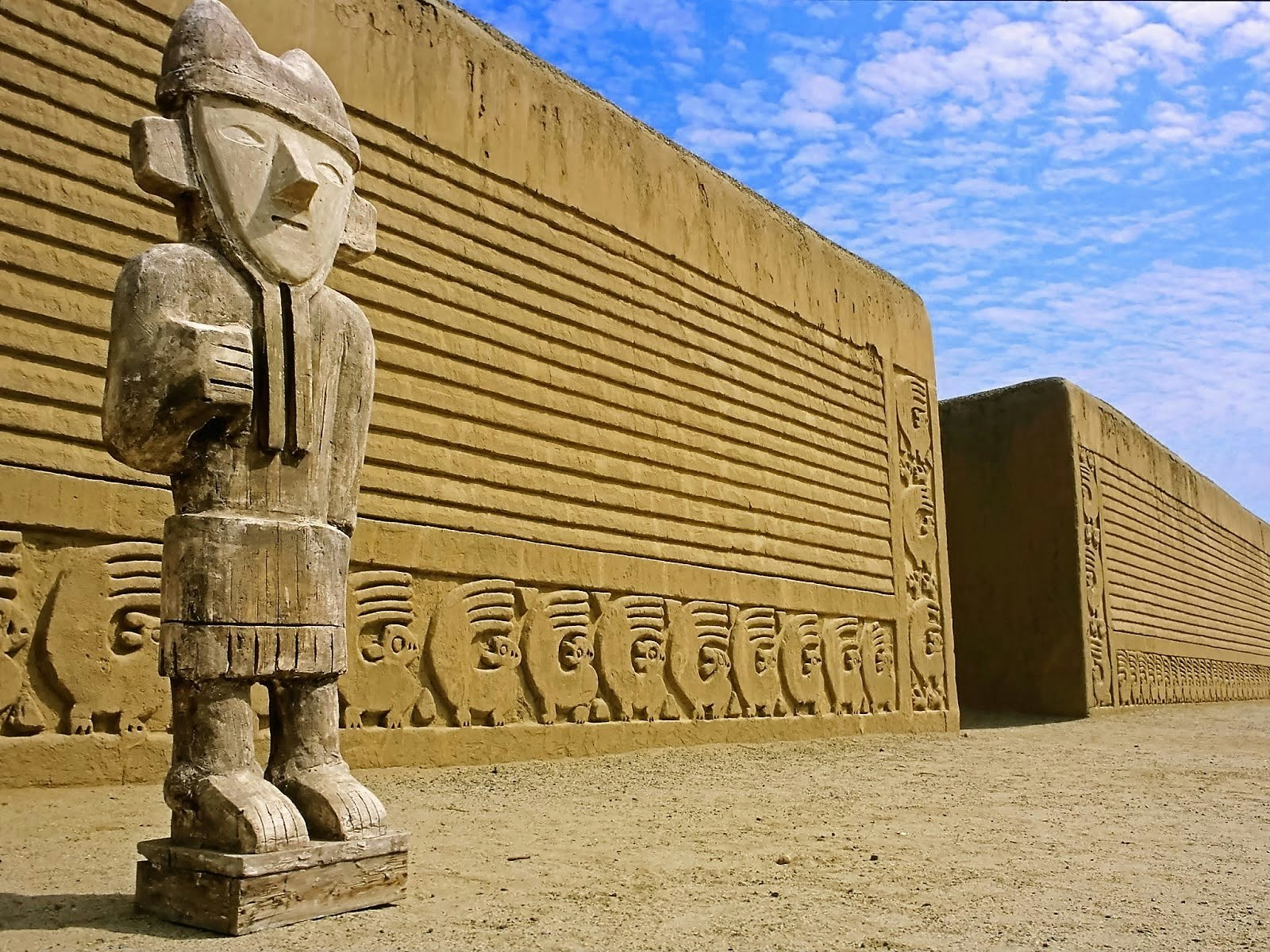 A closeup of an adobe statue in Chan Chan, Peru, in front of an adobe wall