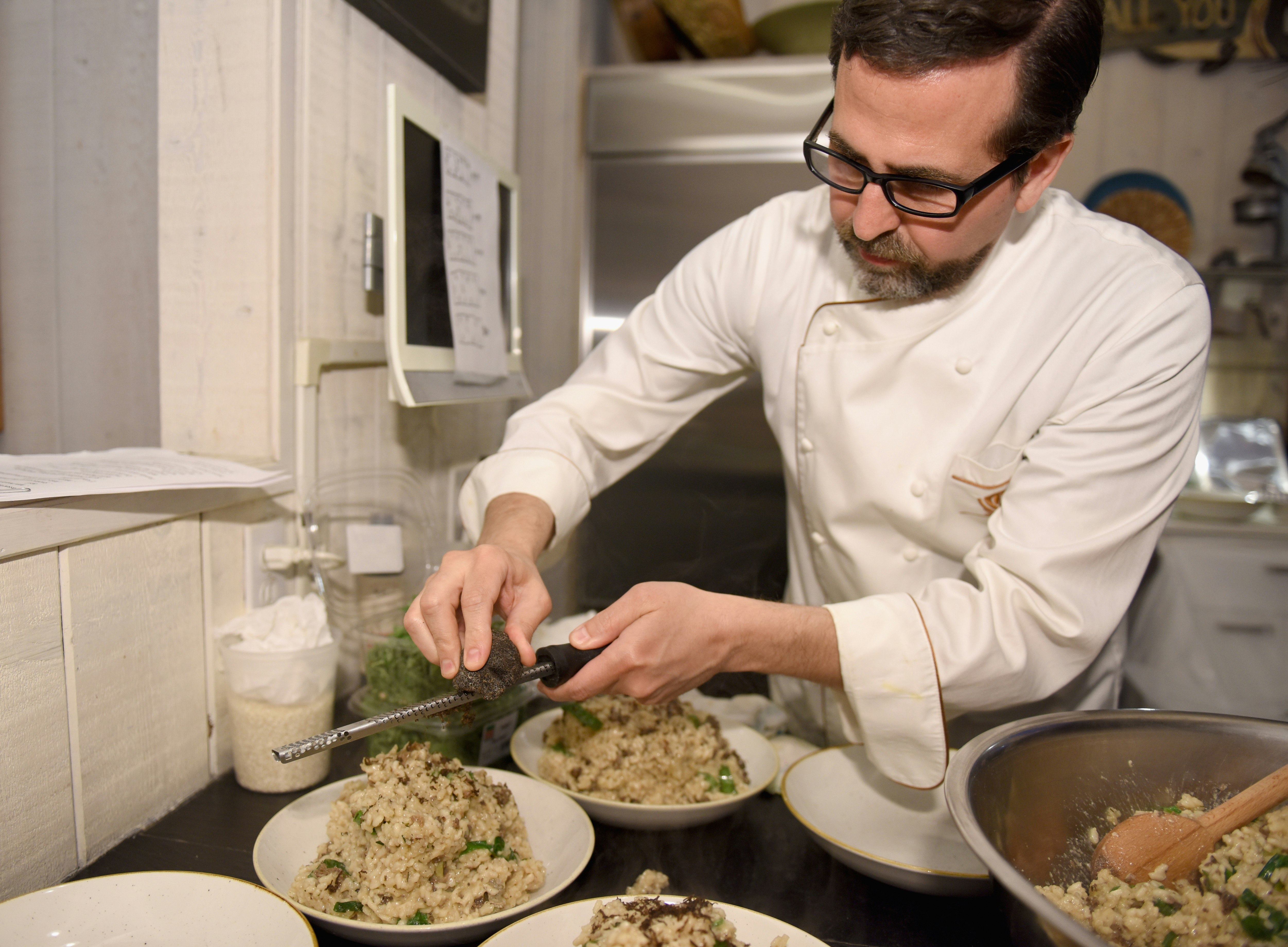 Kocken Tal Ronnen river en krydda över en tallrik vegansk risotto;  LA veganrestauranger  