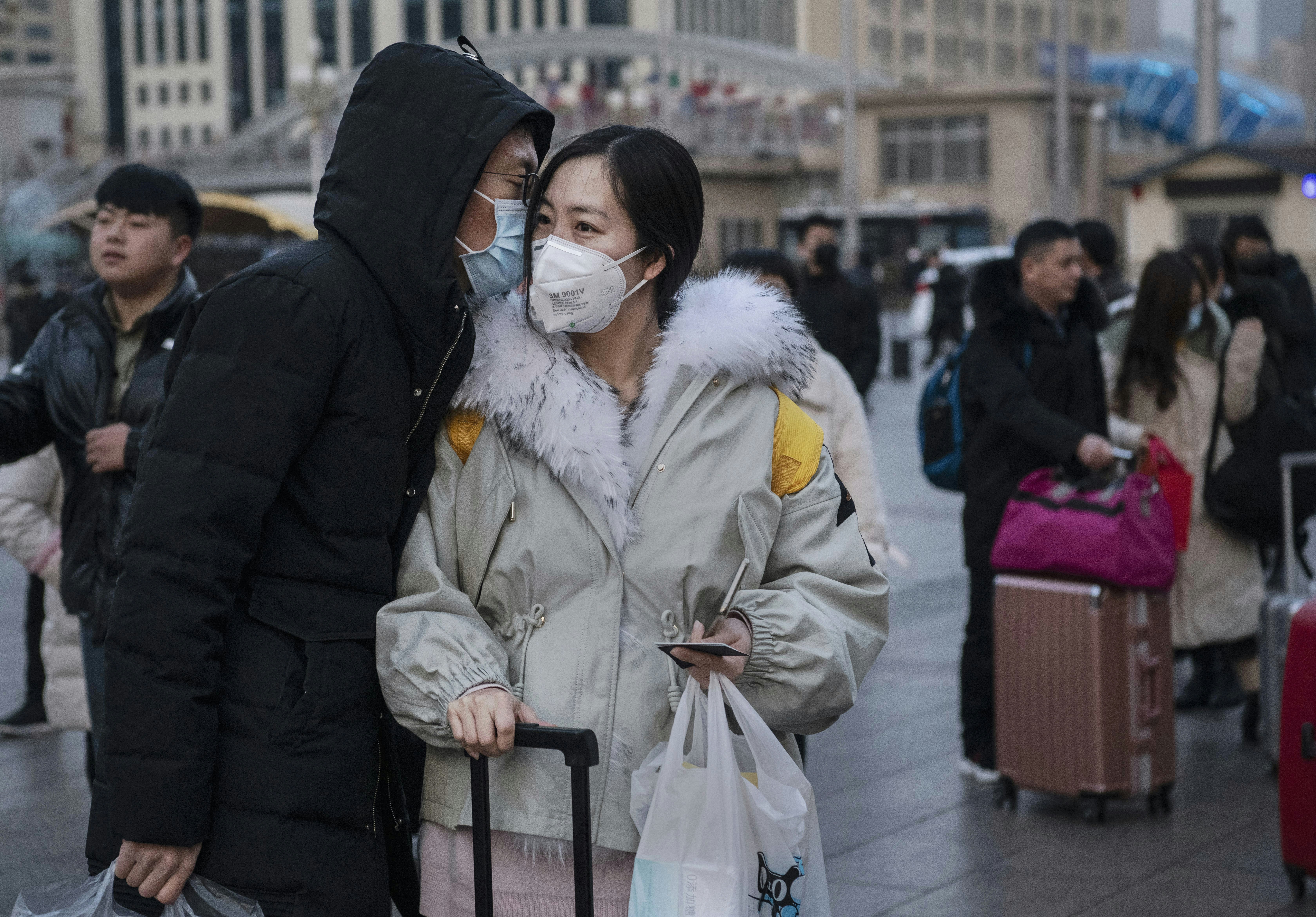 A man kisses his partner goodbye, both wearing face masks, during the coronavirus pandemic in Beijing.