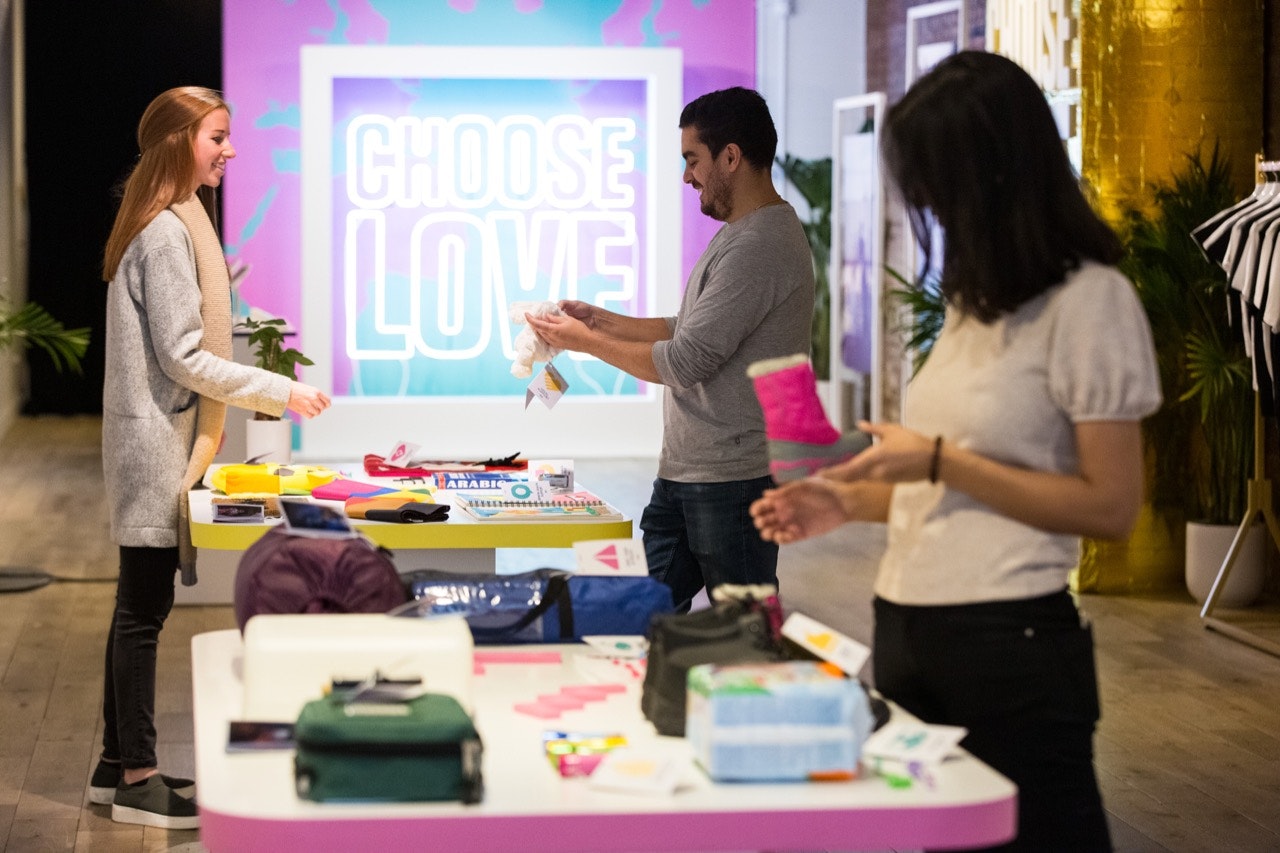Three people shopping at the NYC Choose Love store, one holding a child's snow boot