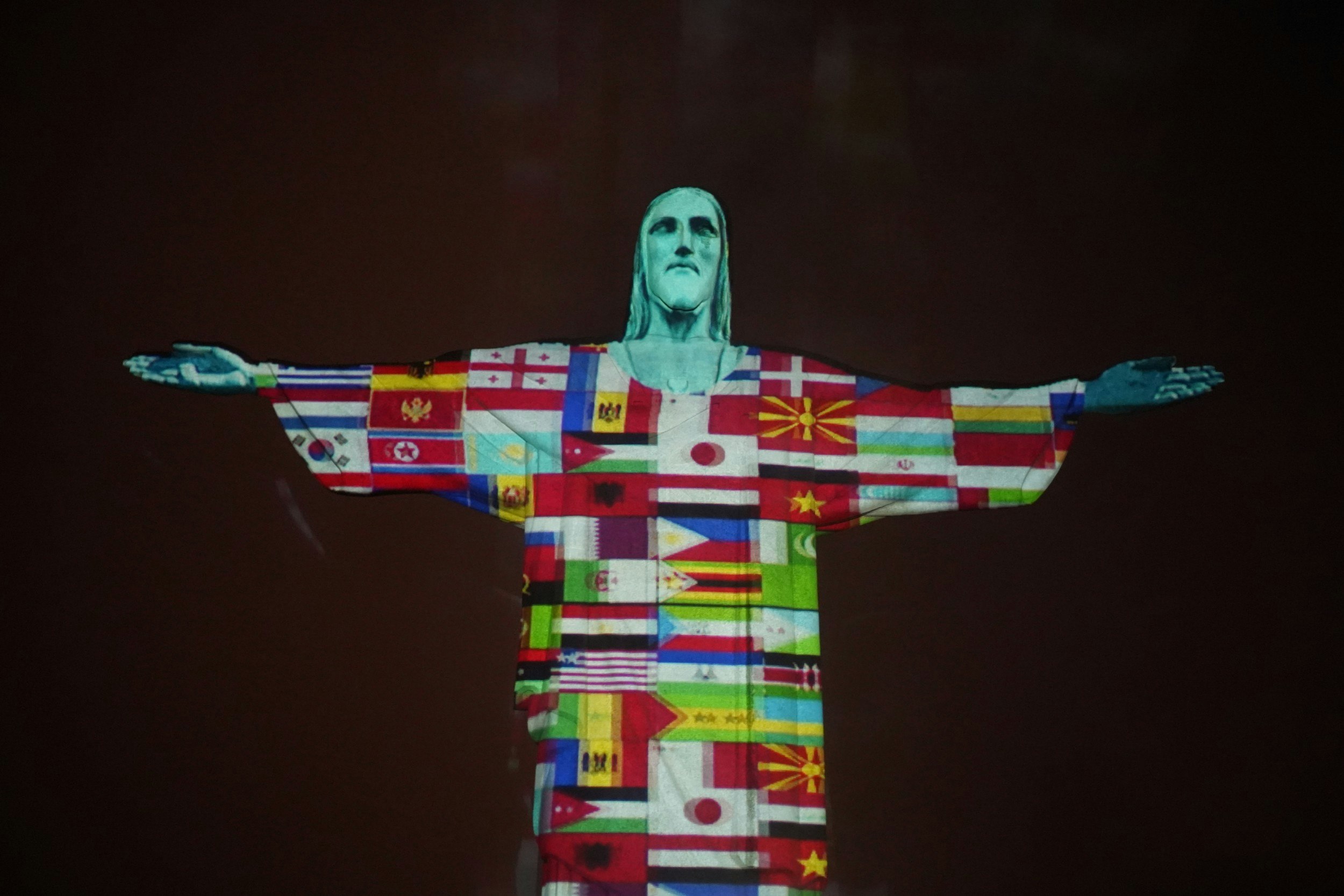 The Christ the Redeemer illuminated with flags of the world