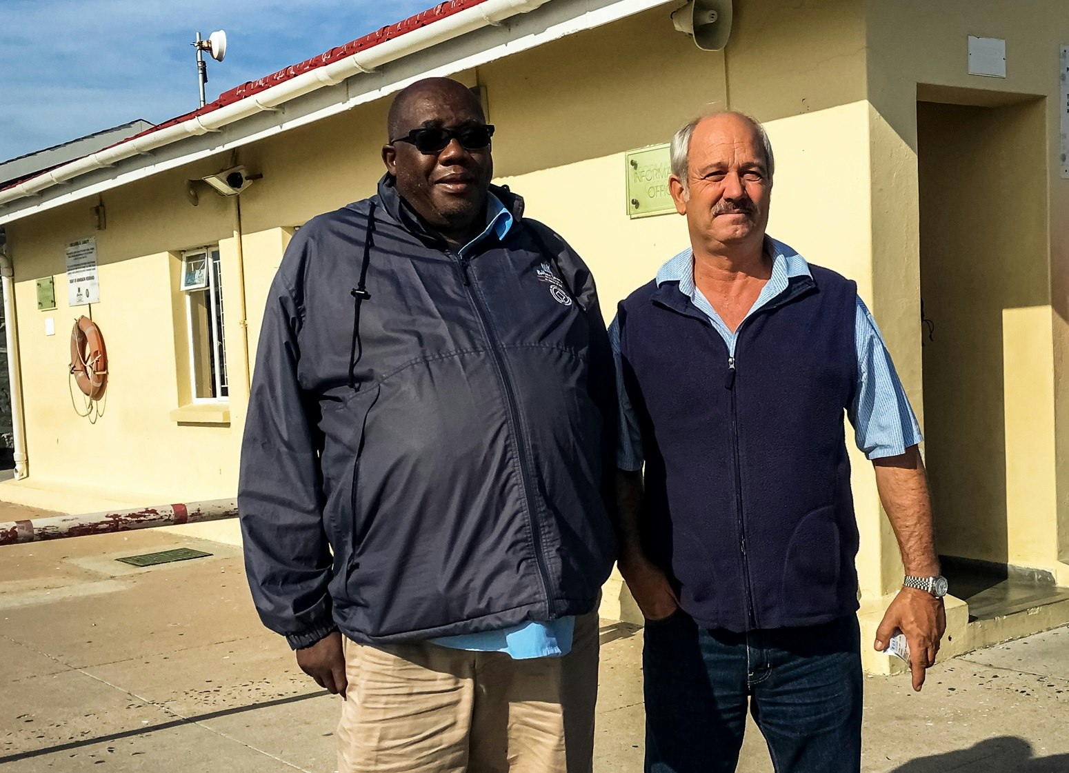 Christo Brand and Thulani Mabaso stand next to each other on the grounds of Robben Island prison.