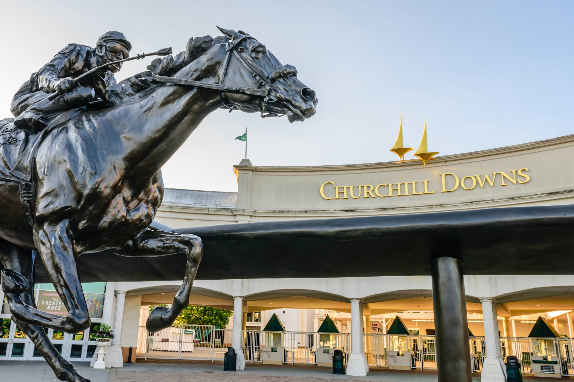 A statue of a jockey riding a horse sits outside the entrance to Churchill Downs. 