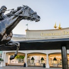 A statue of a jockey riding a horse sits outside the entrance to Churchill Downs.