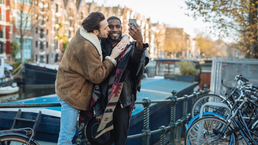 Two gay men take a selfie in front of a canal in Amsterdam