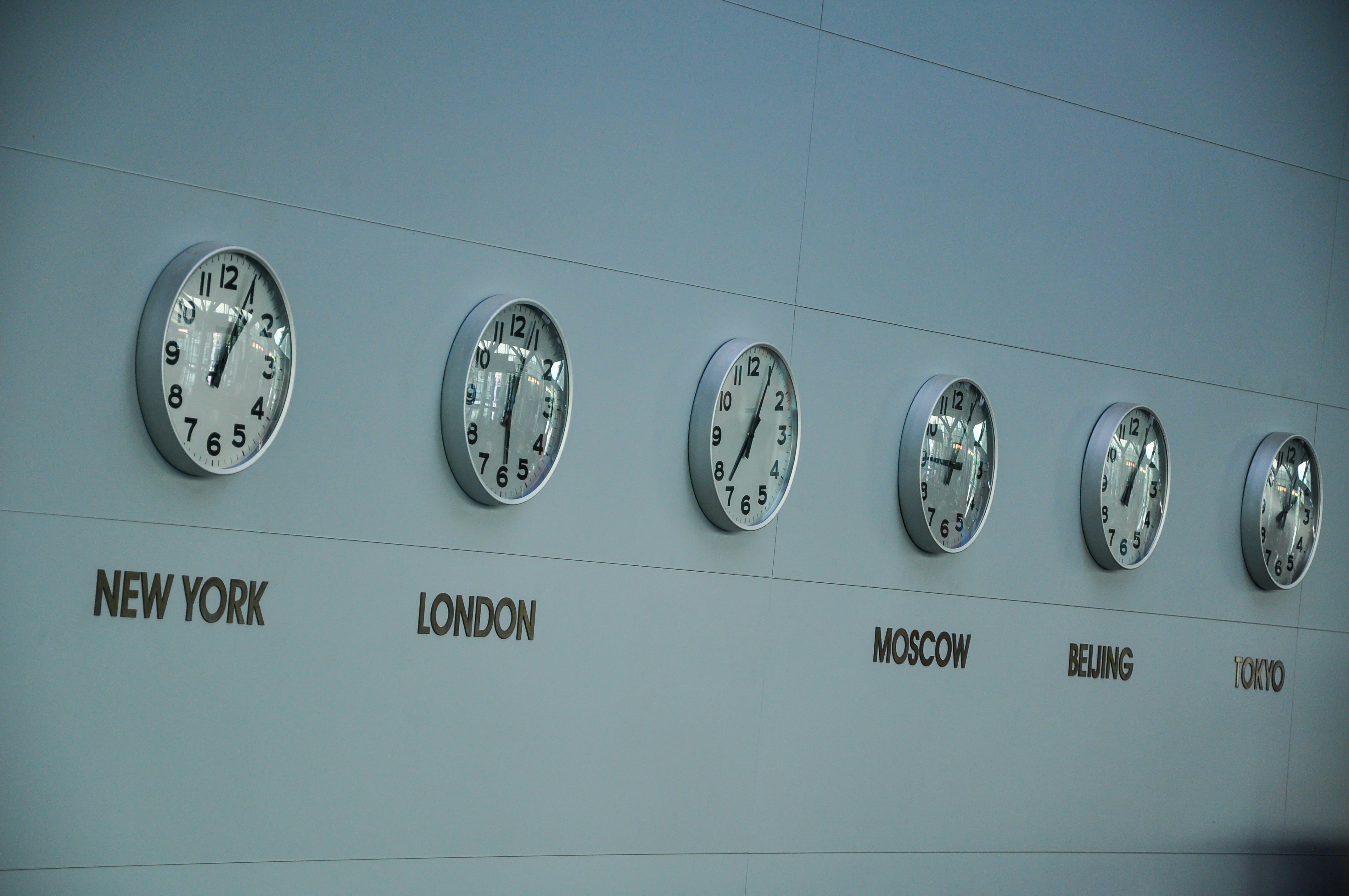A wall of clocks in airport showing various time zones across the world