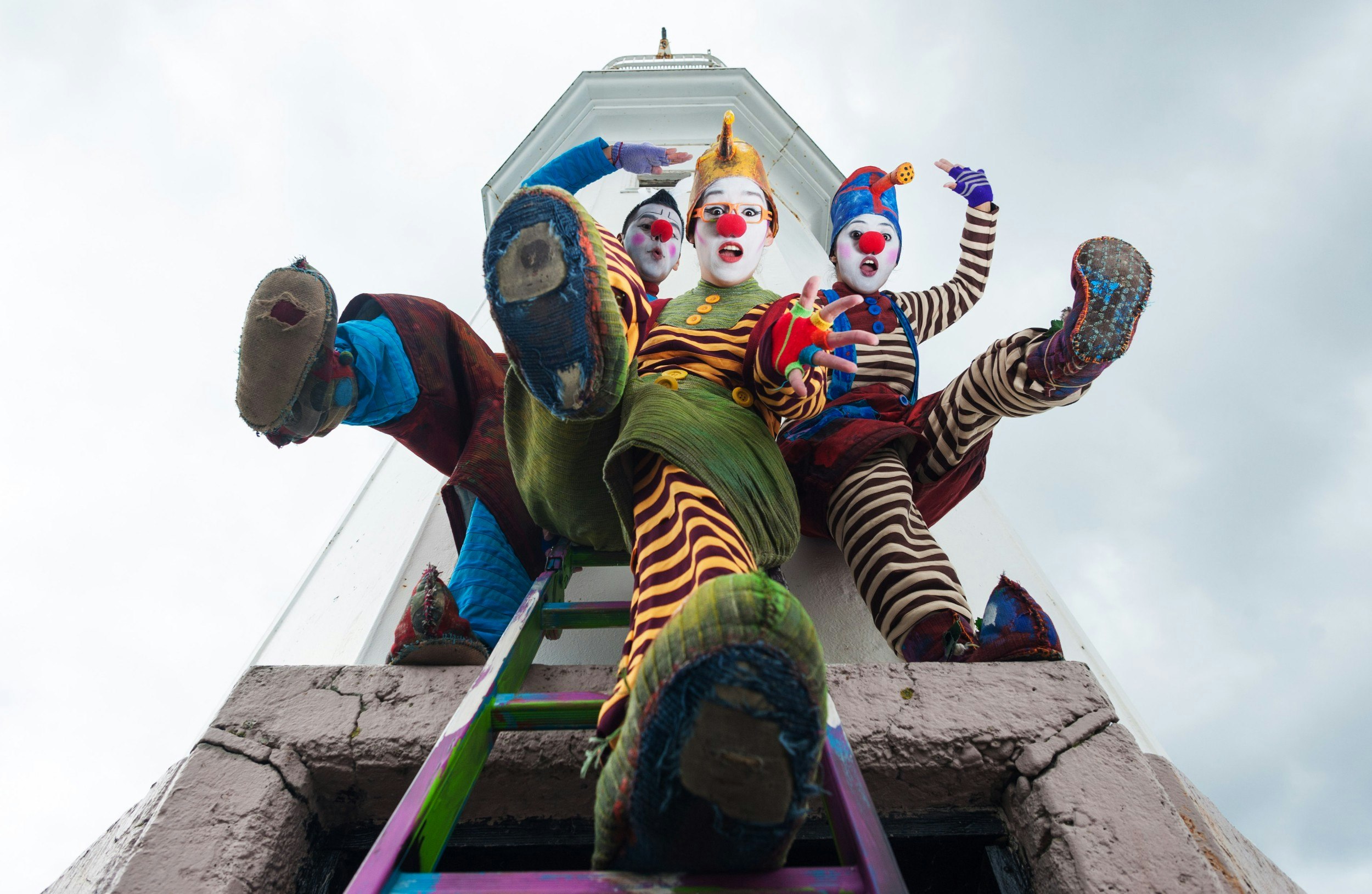 Three people dressed as clowns performing for a photocall