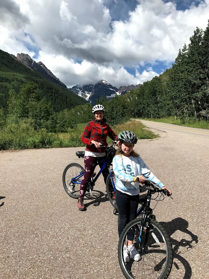 A woman and her daughter stand with mountain bikes in the mountains