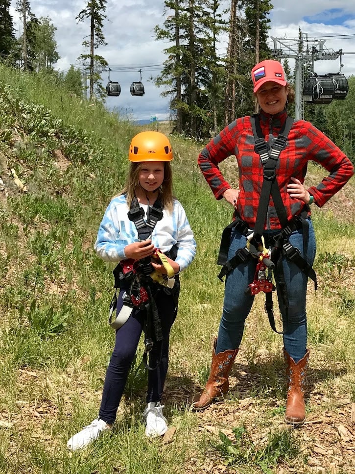 A woman and her daughter strapped in harnesses with smiles on their faces