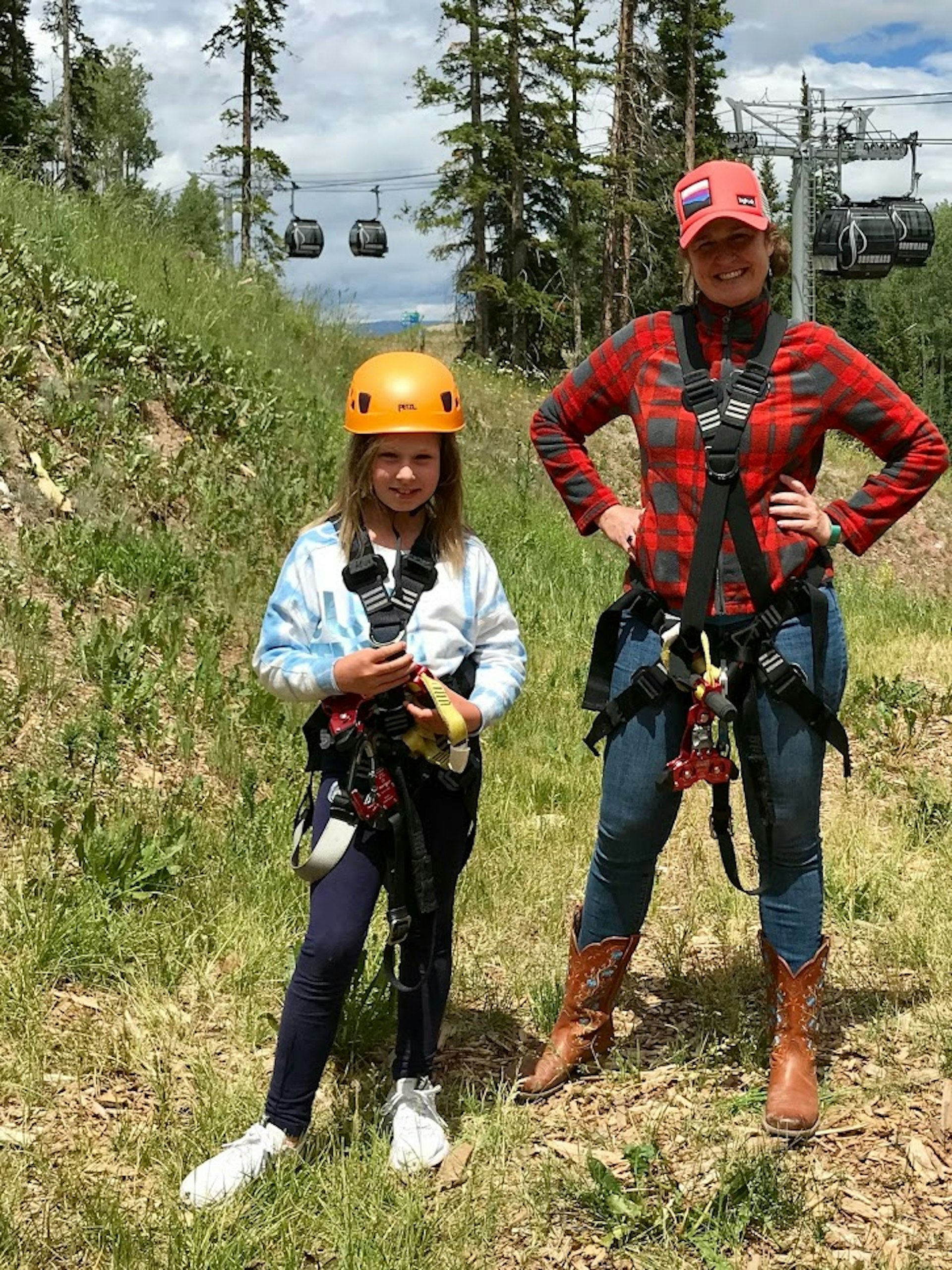 A woman and her daughter strapped in harnesses with smiles on their faces