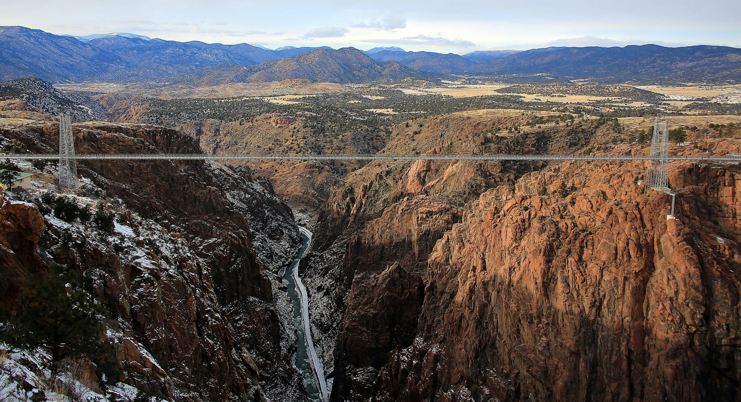 A suspension bridge stretches across a gorge thousands of feet deep in Colorado