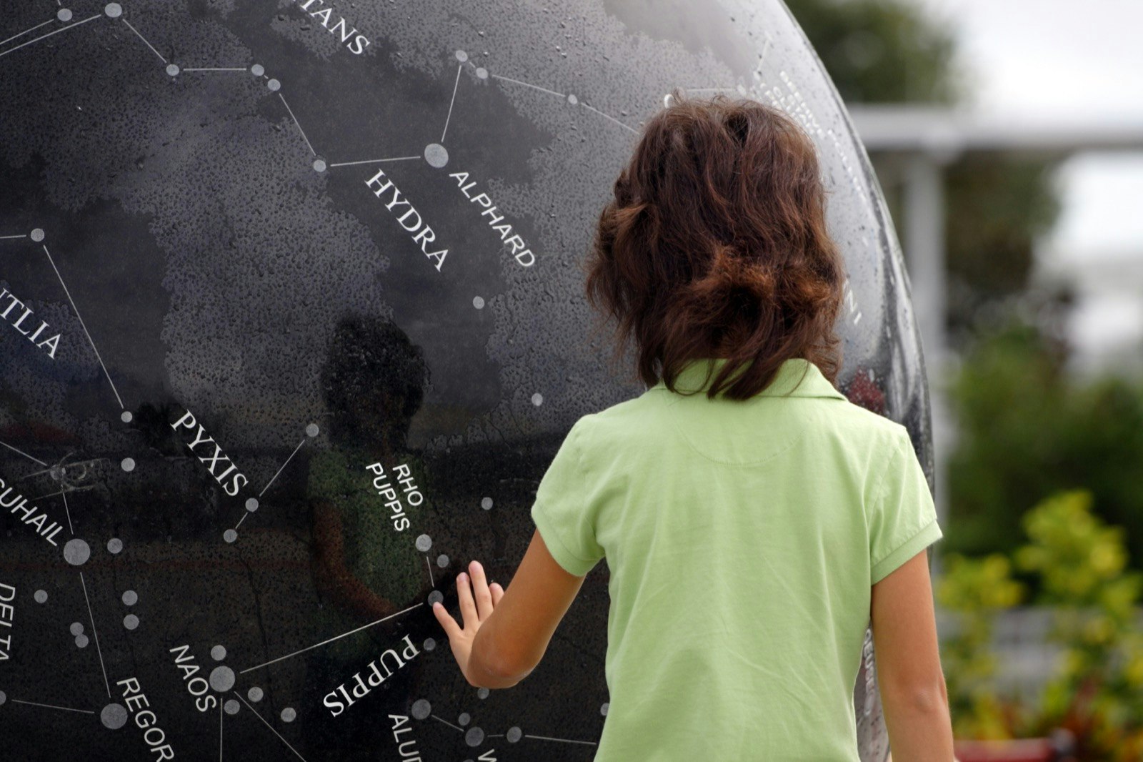 Child points out constellations on a black globe at the Kennedy Space Center