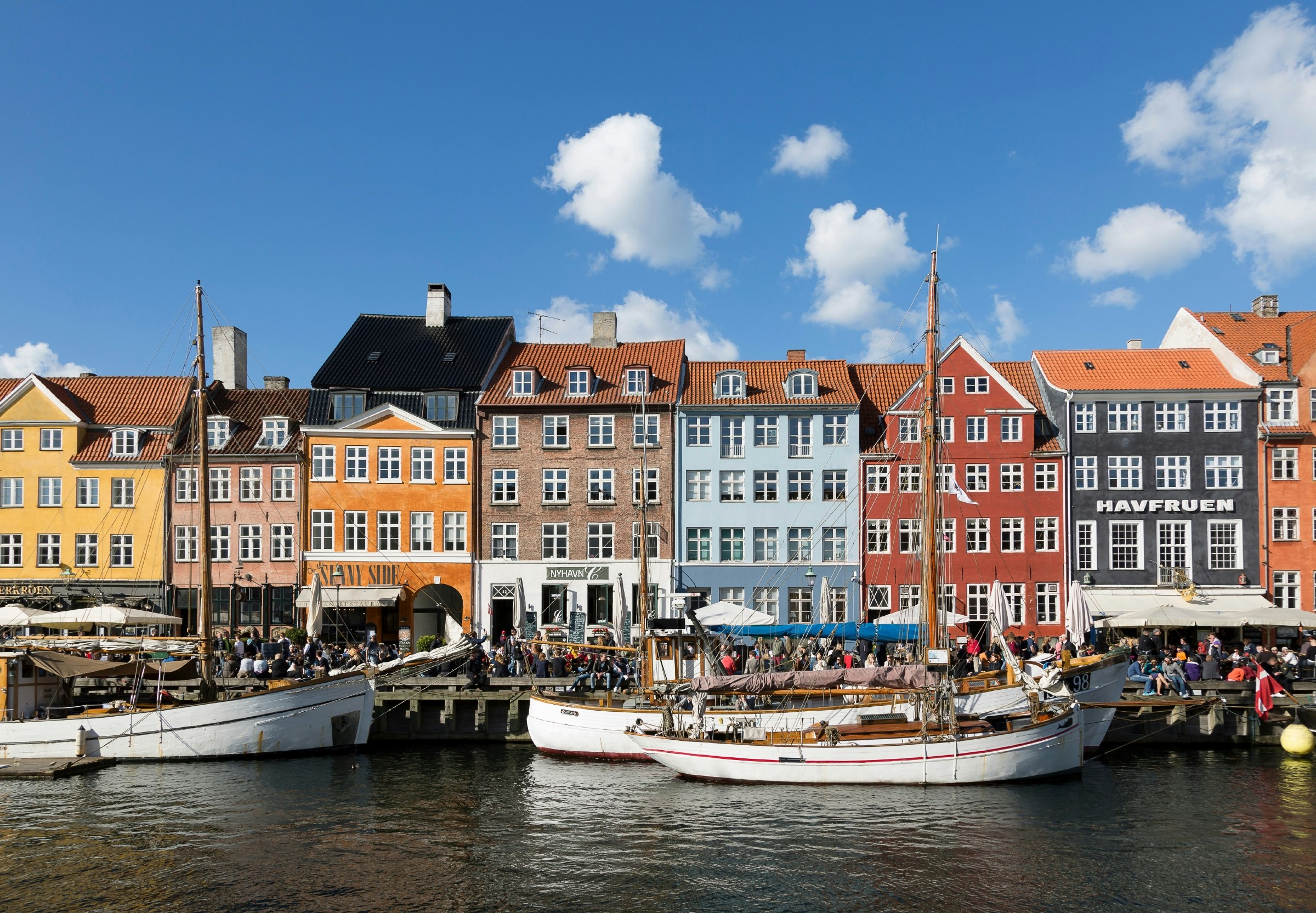 Boats in front of brightly colored building facades on Nyhavn canal in Copenhagen.