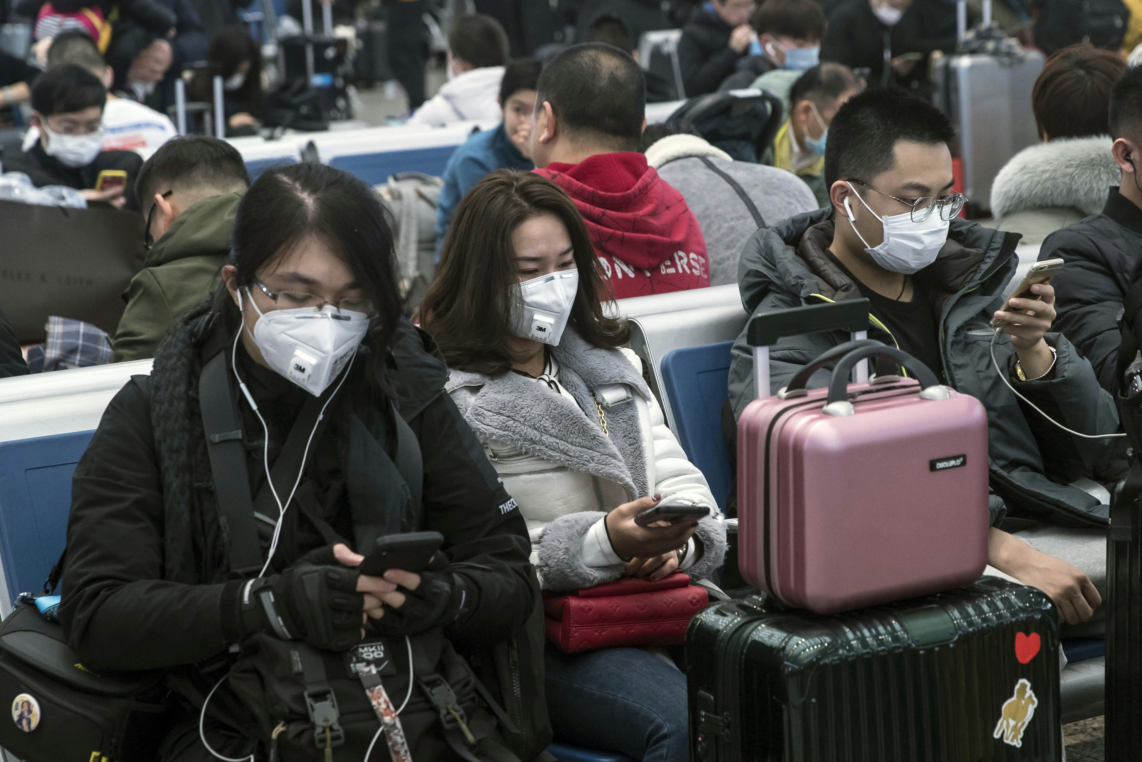 Travelers wearing face masks and pushing suitcases walk through the check-in hall at the Hong Kong International Airport in Hong Kong.