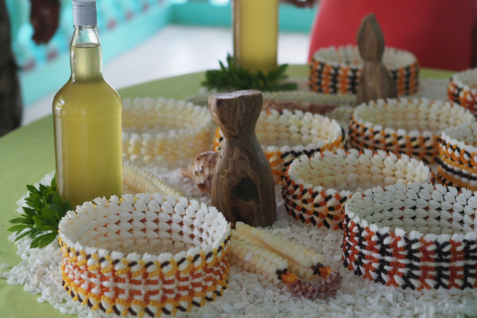 Several bracelets crafted from white and coloured shells from Anaa displayed on a table.