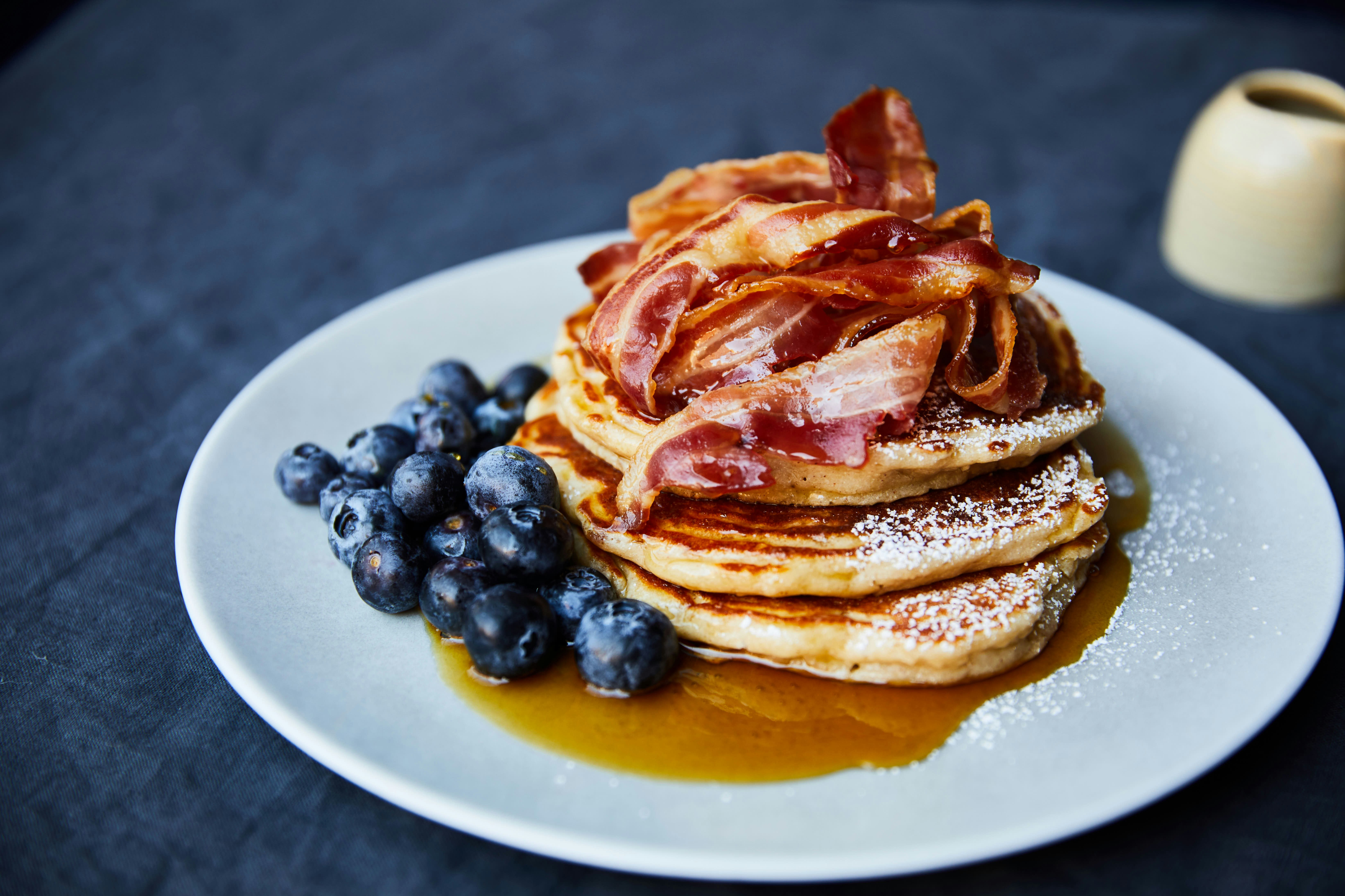 Stack of pancakes with side of blueberries covered in syrup