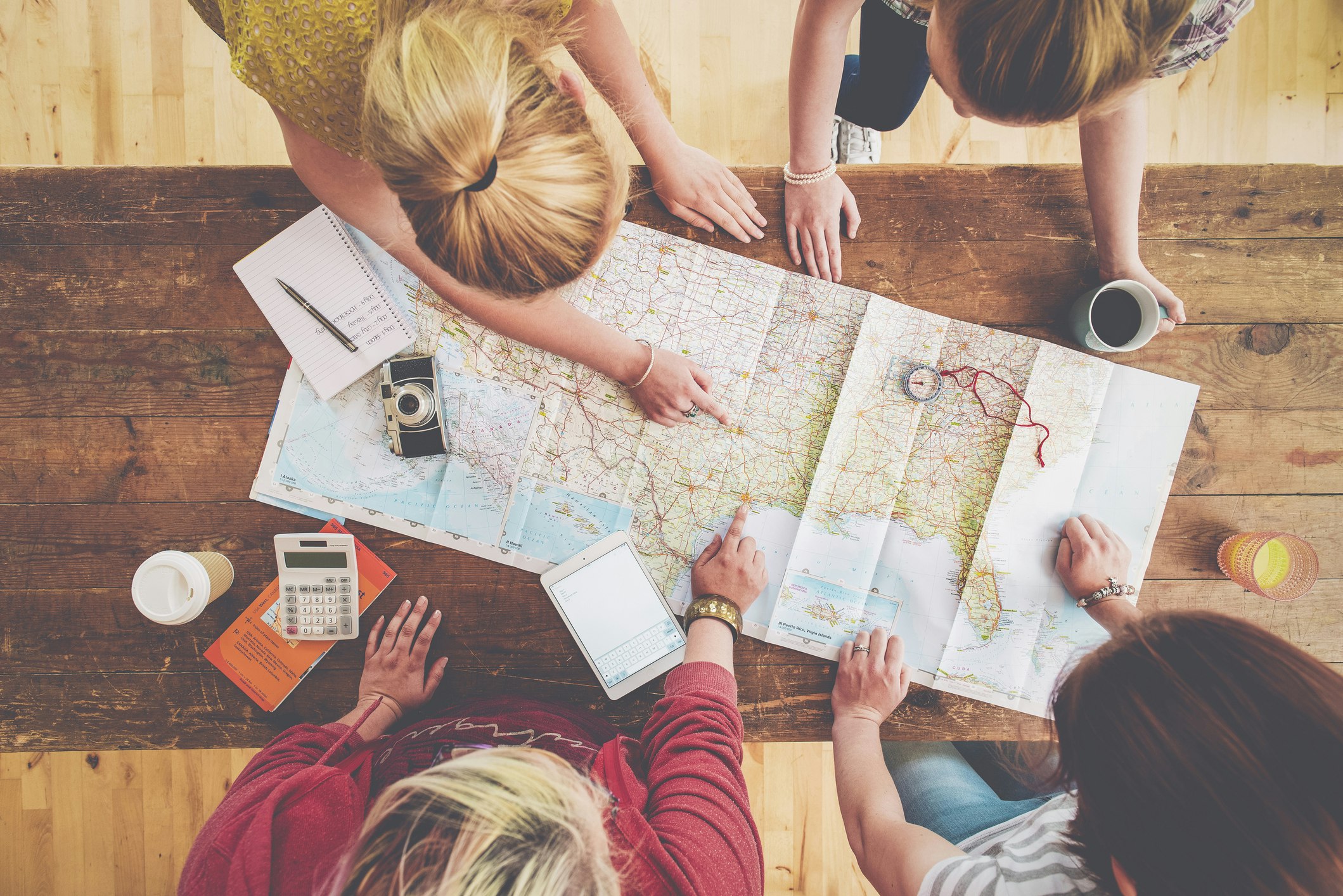 Women planning trip with map on wooden table
