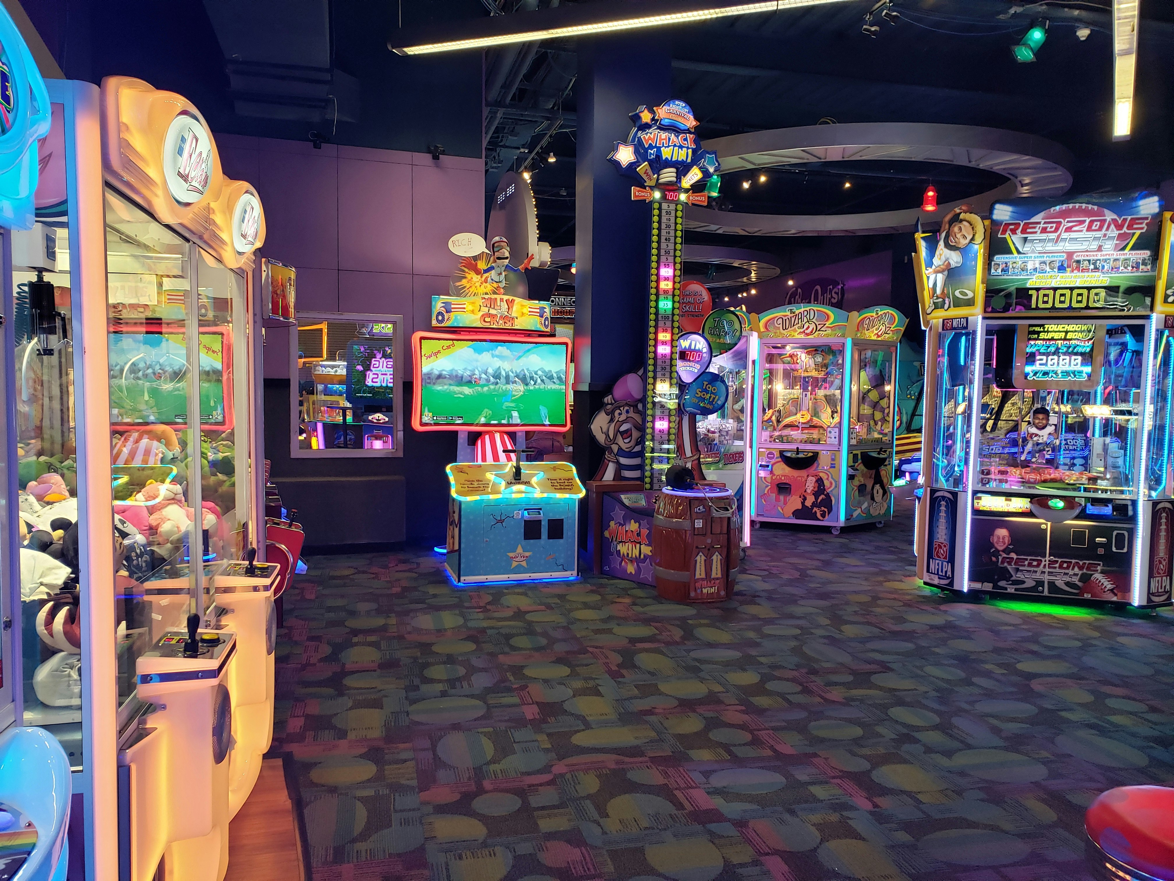 The Kids Quest area at Mohegan Sun is full of colorful arcade games, crane machines, and carnival attractions set against light purple walls and an abstract patterned carpet in shades of purple and green