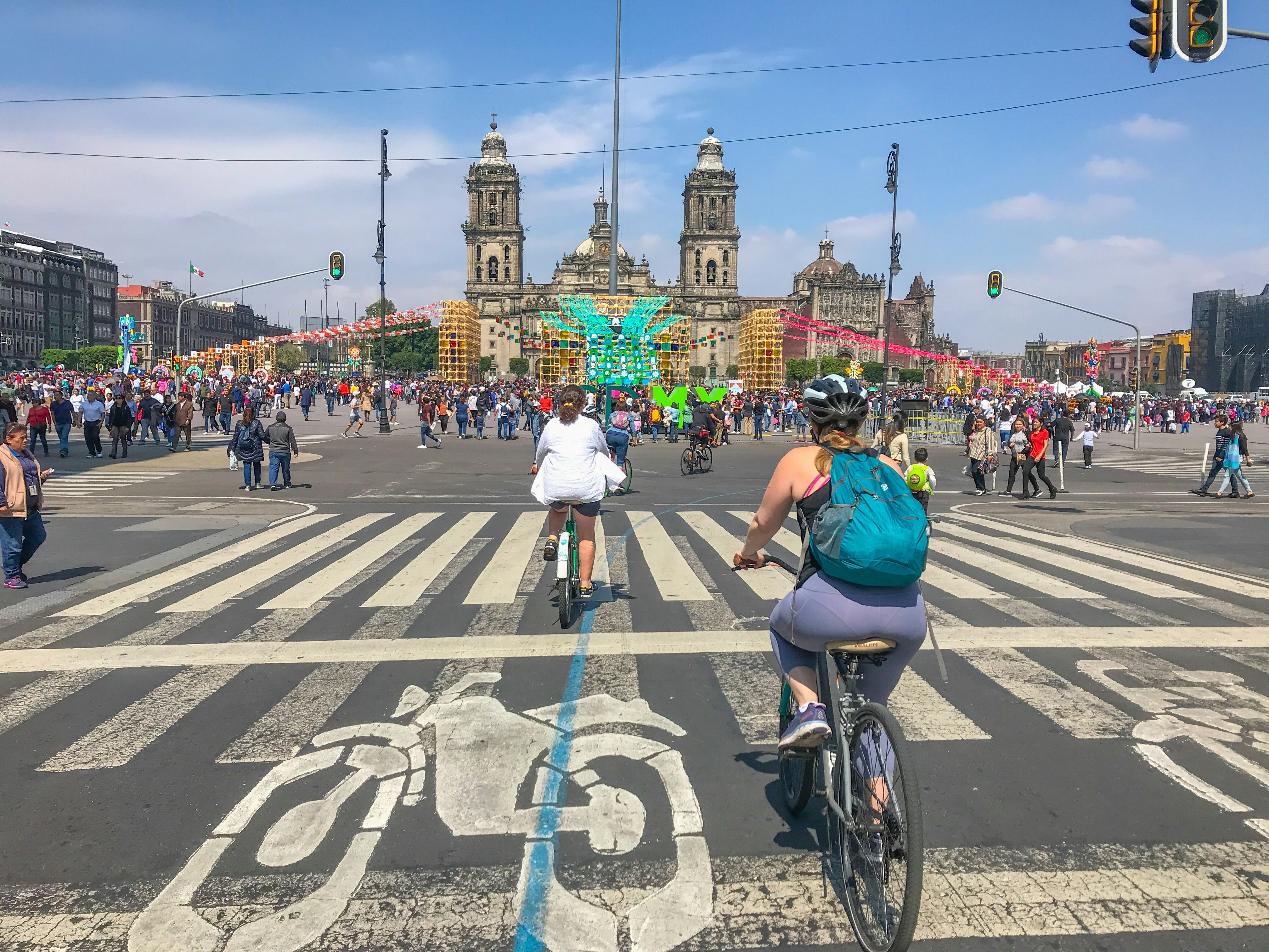 people riding bikes in front of the Zocolo in Mexico City