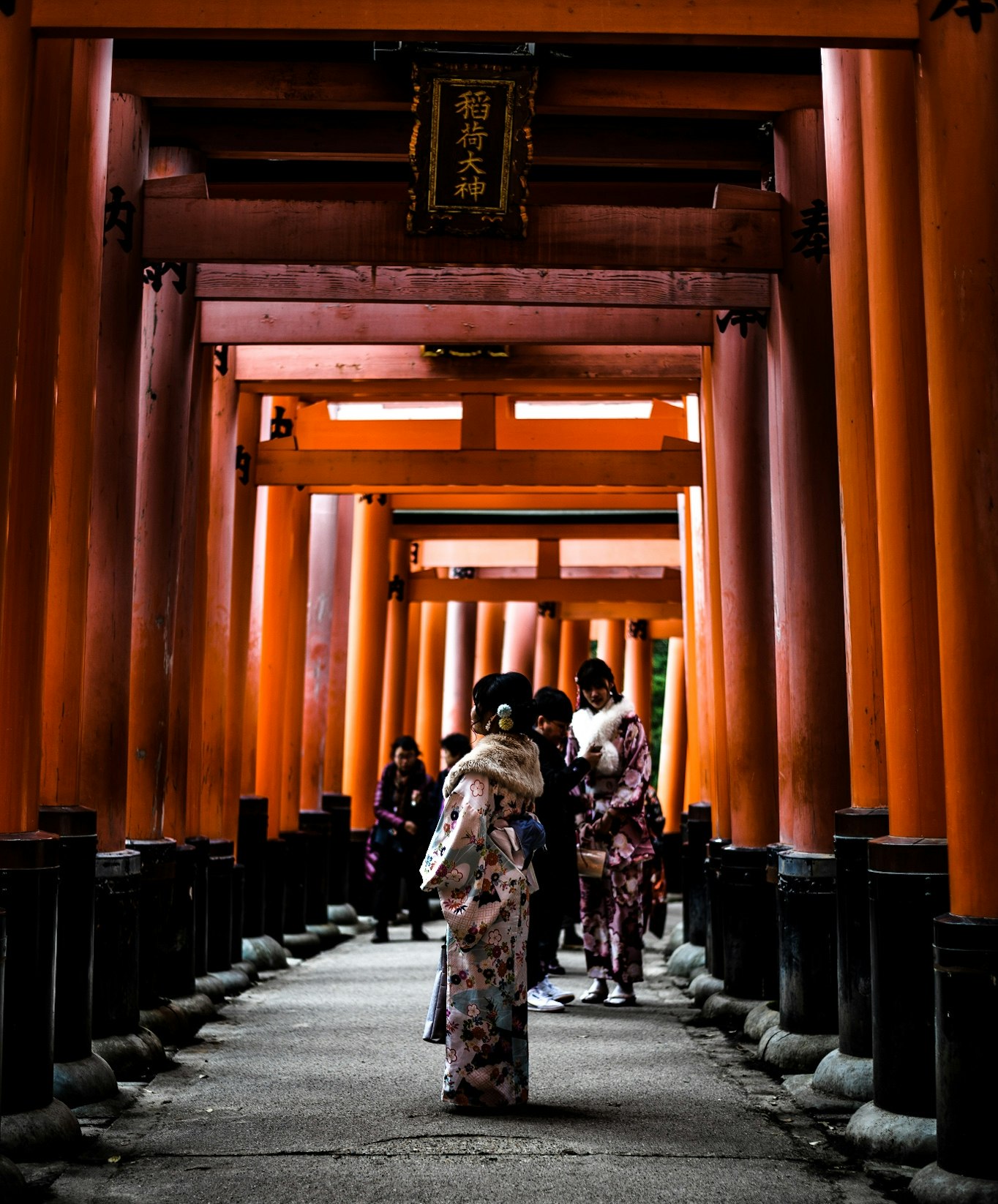 A woman in a colourful, floral-patterned dress stands in a tunnel in Tokyo, staring into the distance.