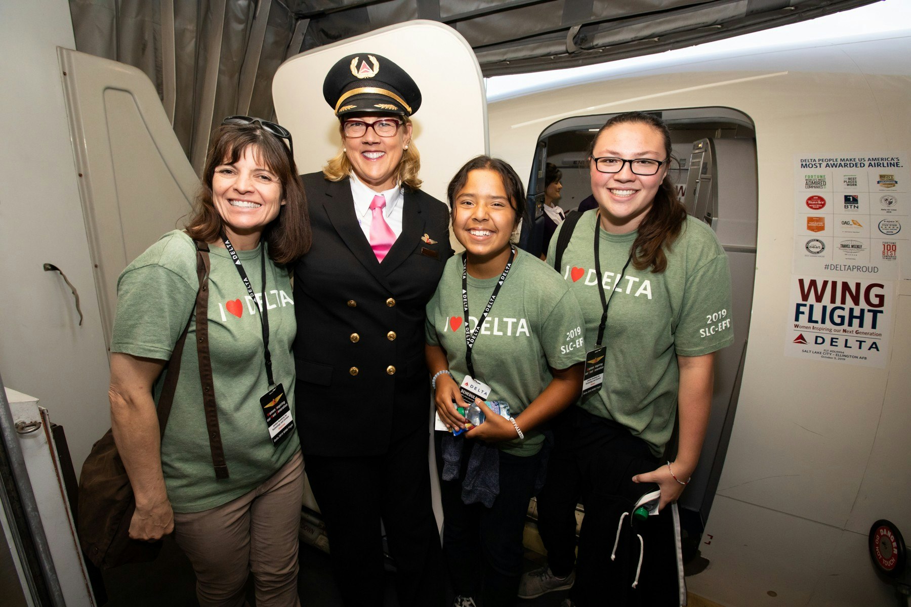 Three young girls with a female pilot at the door of a Delta plane