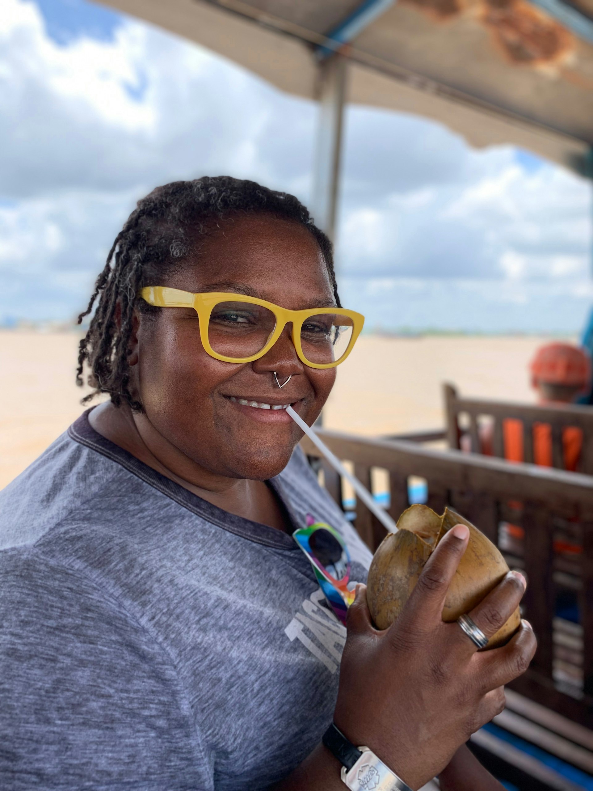 A woman sips a drink with a straw out of coconut in a boat on the Mekong River in Vietnam; traveling after pulmonary embolism 