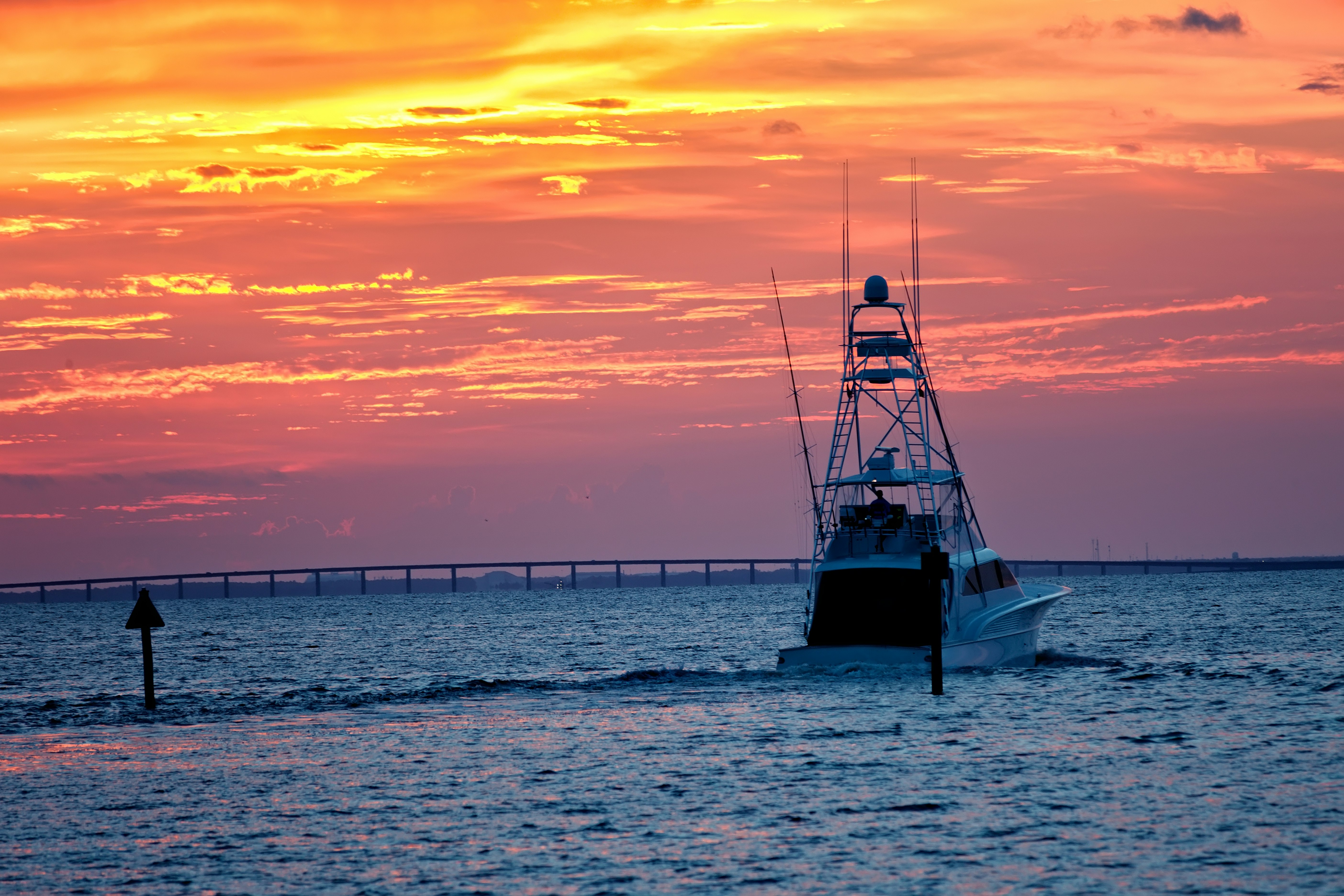 En stor fiskebåt går ut i öppet vatten under solnedgången i Destin, Florida; ungkarl