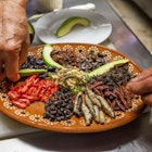 In a Mexican clay plate, a chef is preparing with many different insect dishes from Mexico.