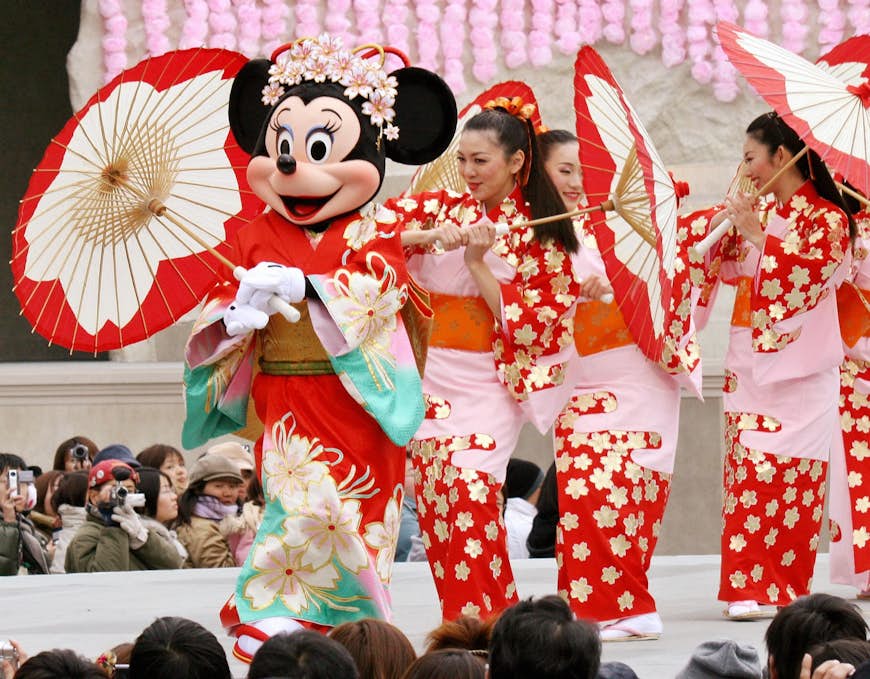 Minnie Mouse and women dance in red flowered dresses 