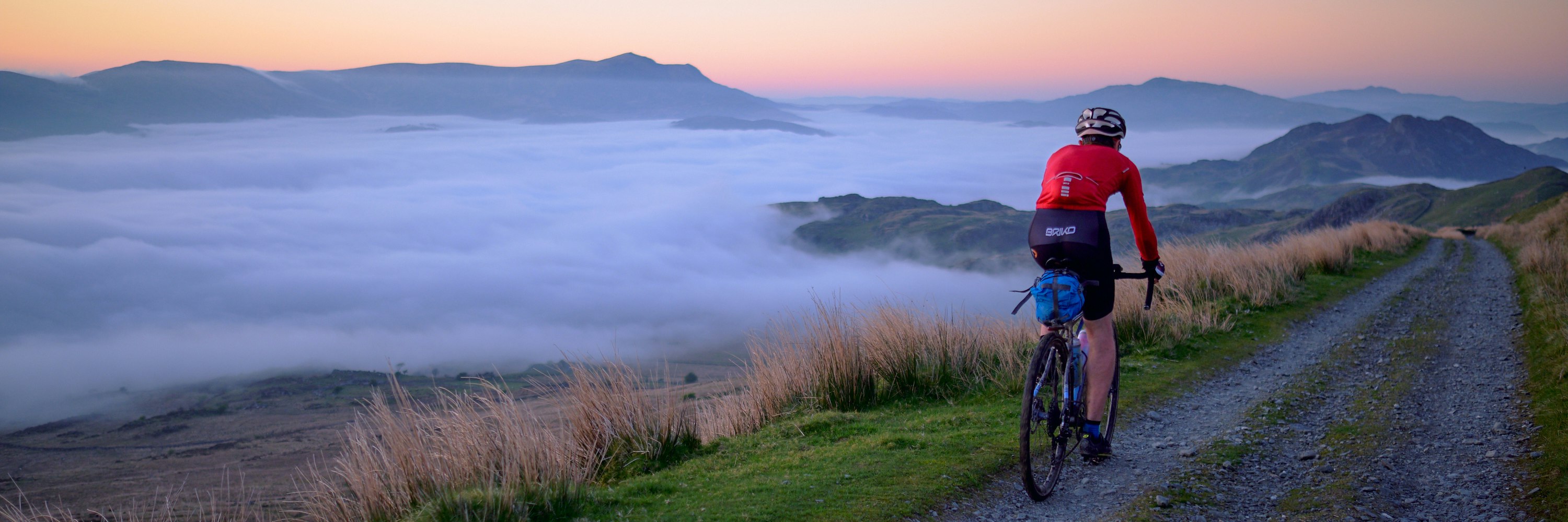 Cyclist travels through mist and mountain peaks in Dogellau, Wales