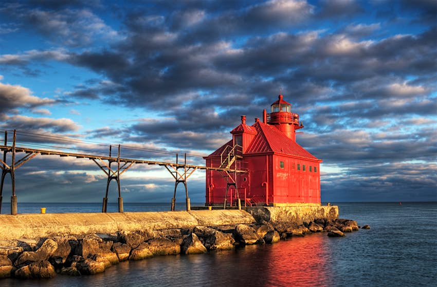 A bright red lighthouse pokes into Lake Michigan in Door County Wisconsin; Great Lakes road trip