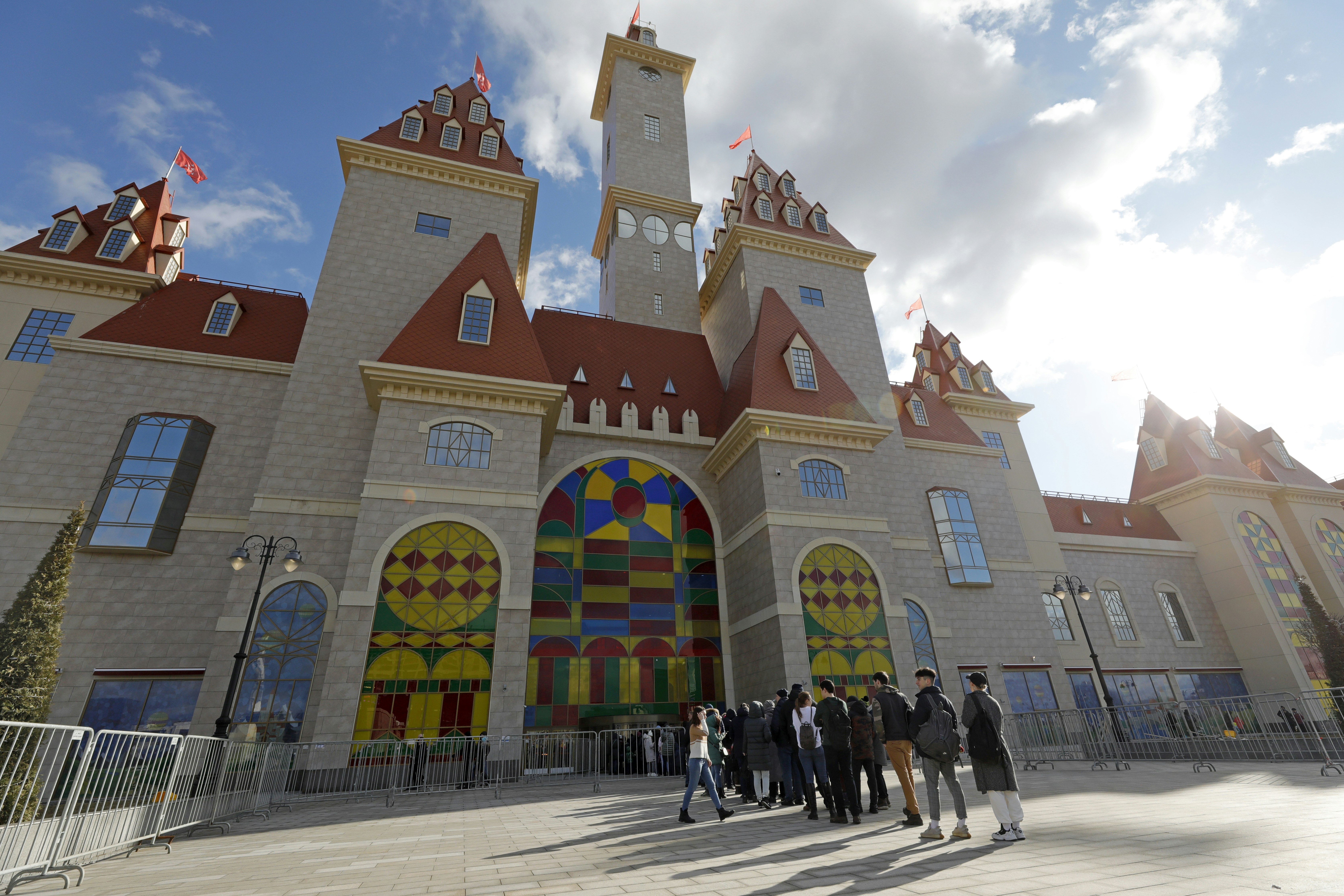 Children queue in front of a fairy tale castle at a theme park in Moscow