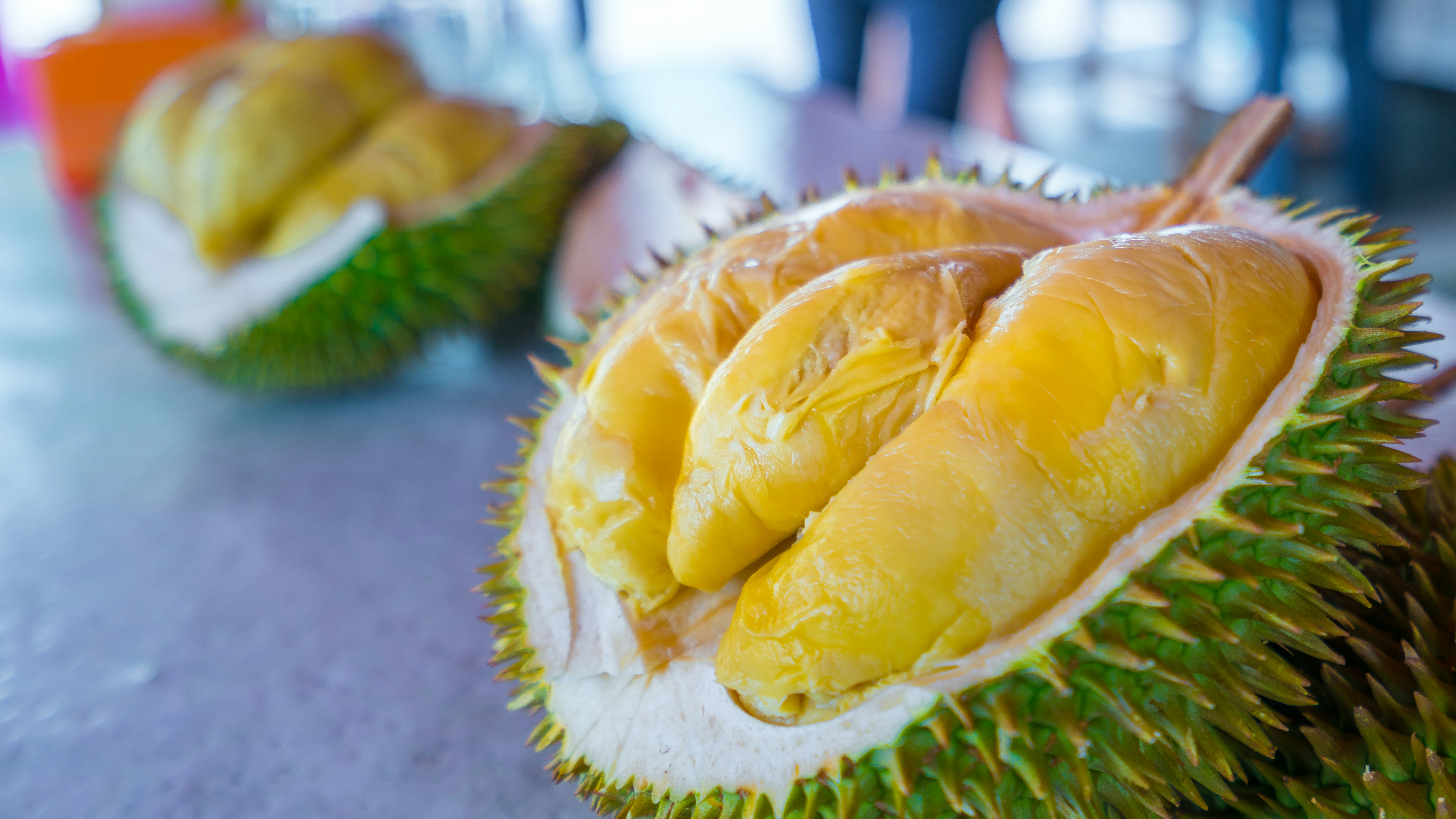 A pair of durian fruits have been cut open to show the fleshy portions